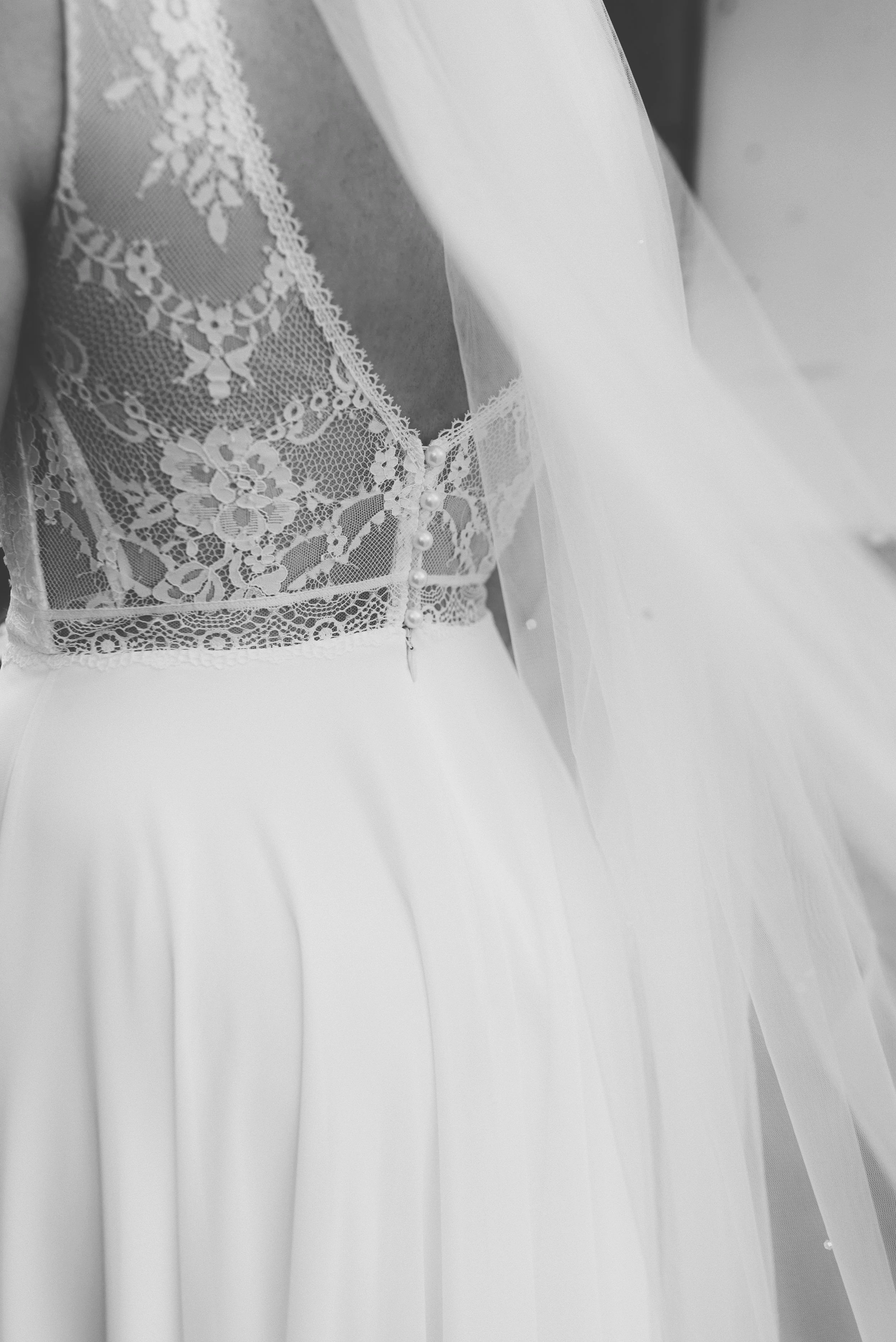 Nahaufnahme eines weißen Brautkleids mit Spitzenmieder und Tüllrock.