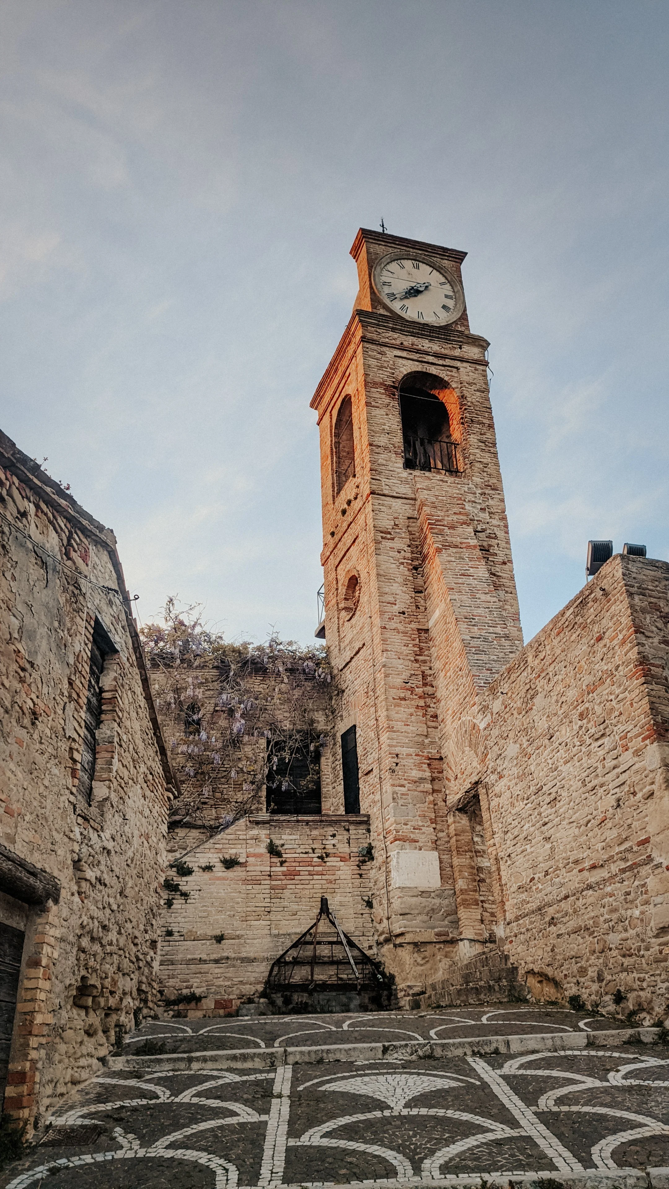 Altstadt mit alter Sandstein Turm und Uhr bei Sonnenuntergang, gepflasterter Platz im Vordergrund.