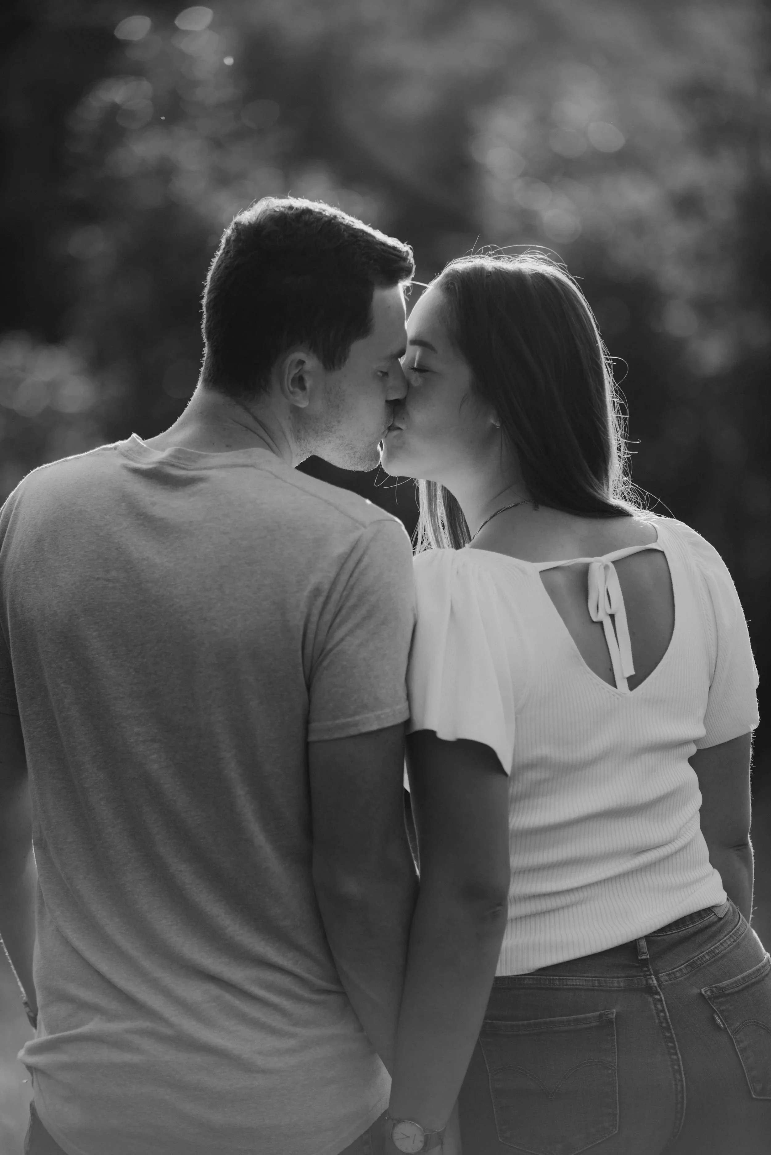 Ein Paar küsst sich im Freien bei Sonnenuntergang, Schwarz-Weiß-Foto.