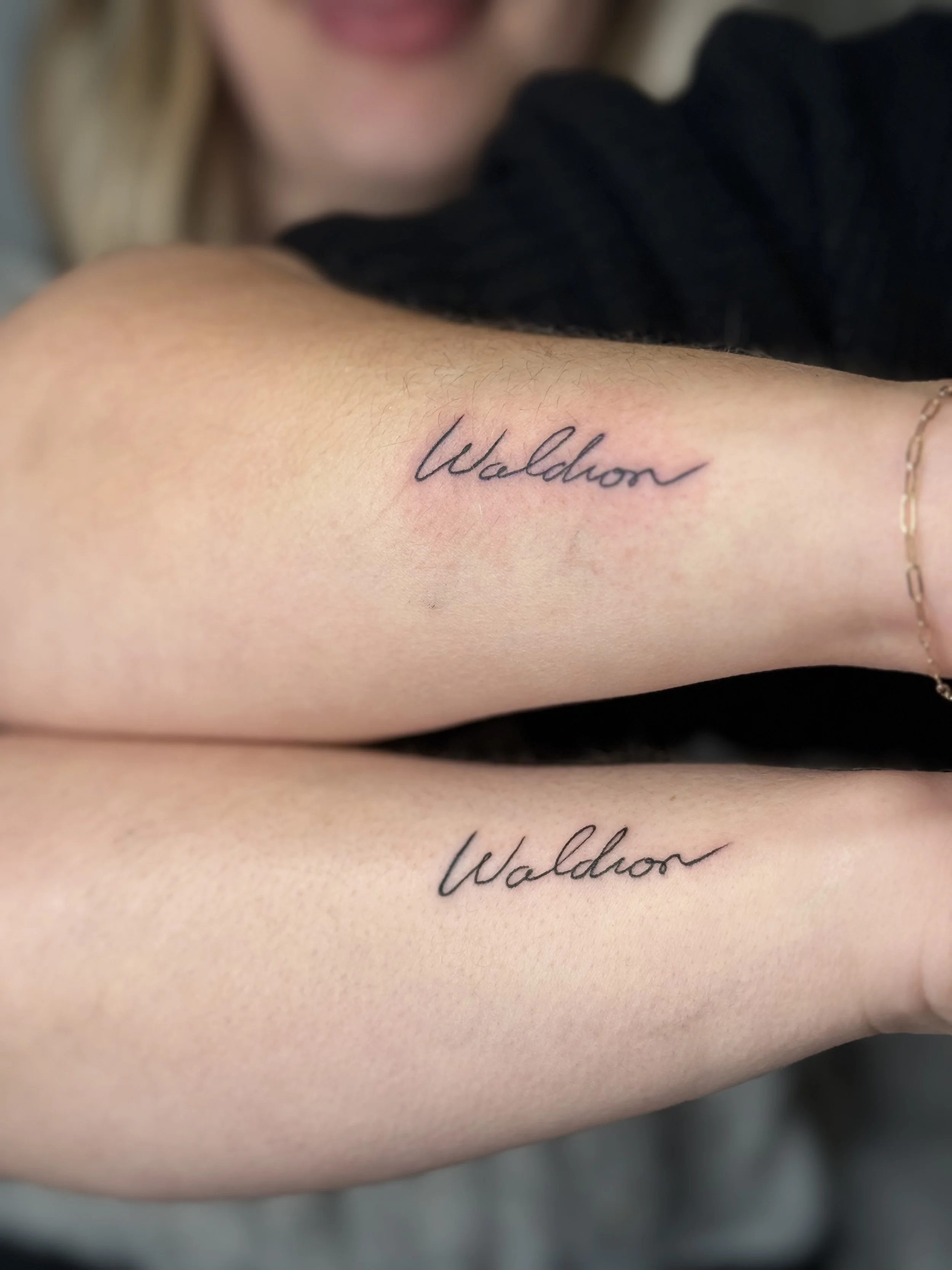 Fine line matching script tattoos placed on thighs in minimalist lettering