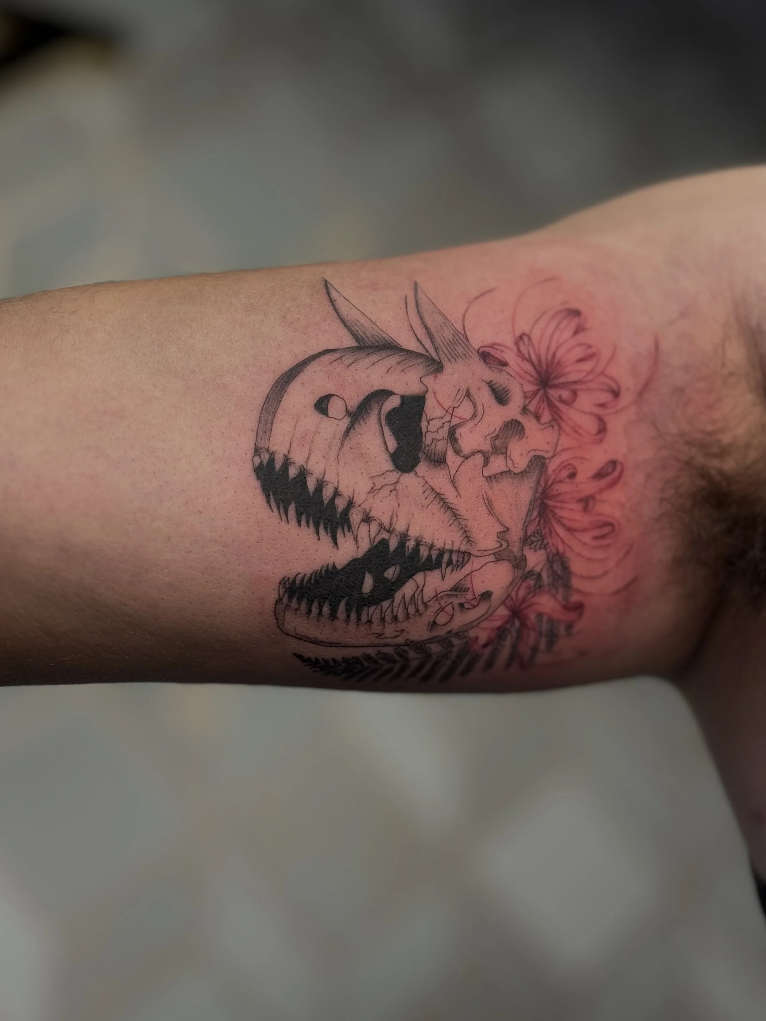Fine line floral skull tattoo with botanical and fern details on forearm