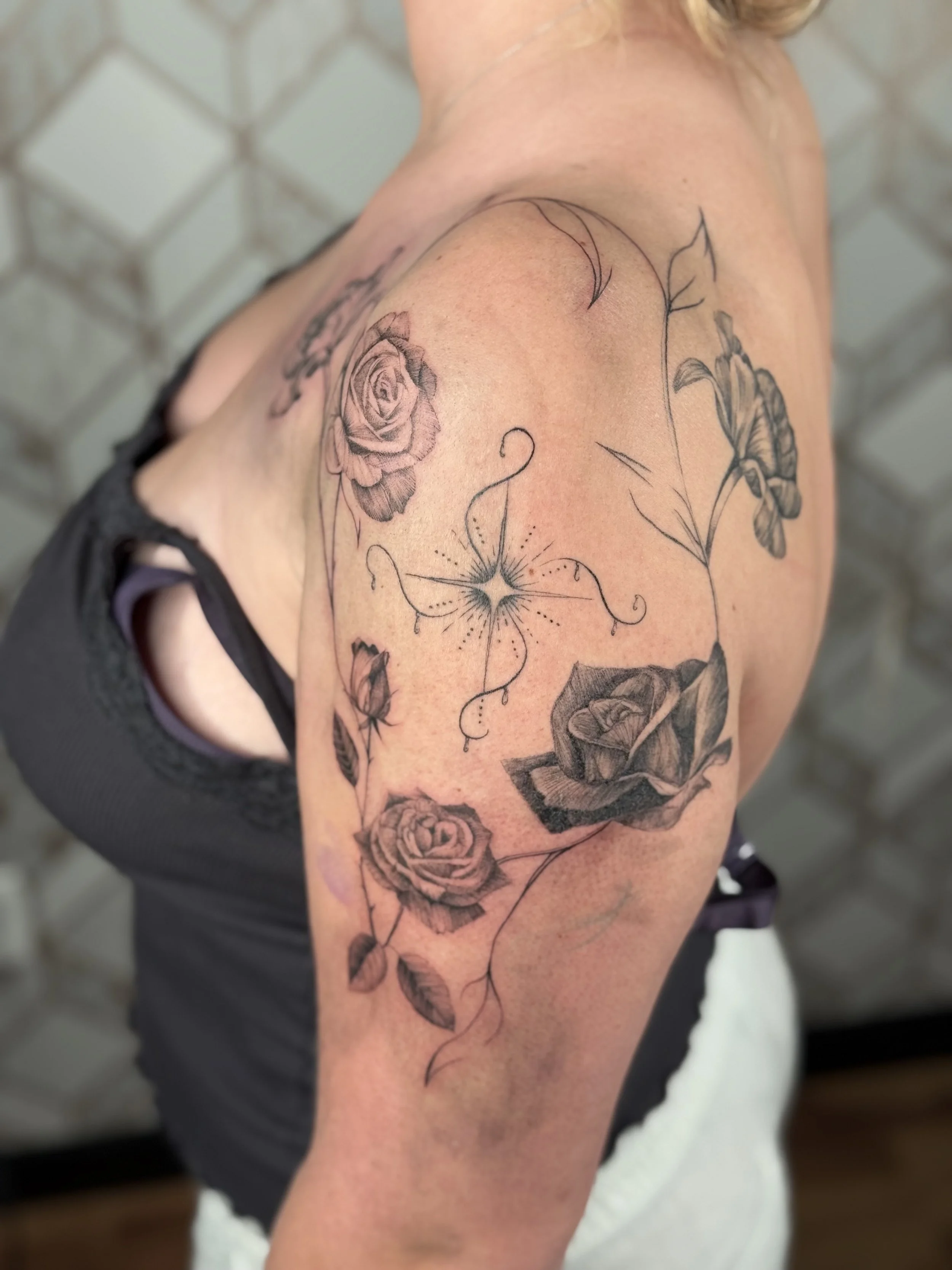 Fine line ornamental floral tattoo with roses flowing across the shoulder by a Dearborn fine line tattoo artist