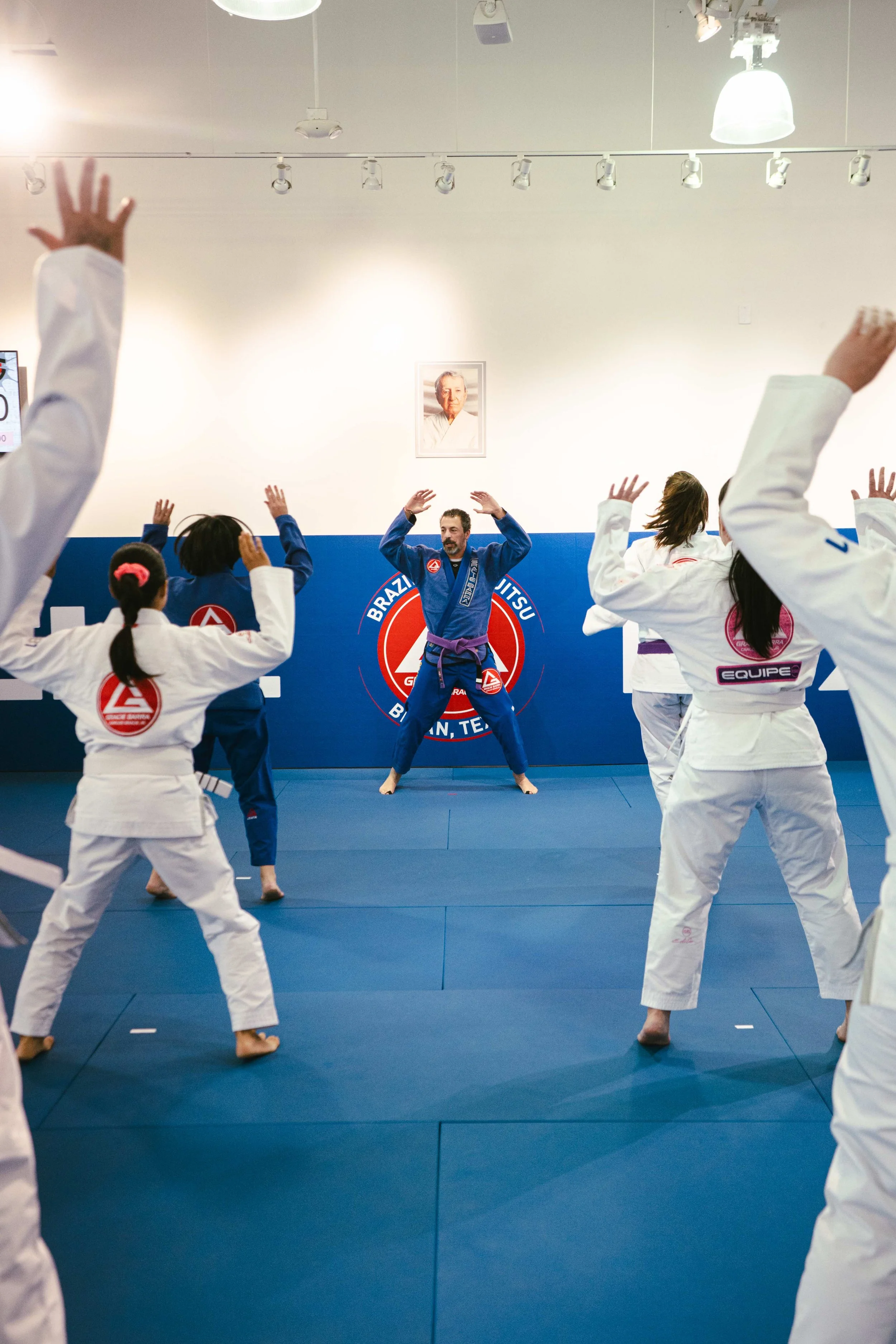 Adult class doing jumping jacks on the mat at Gracie Barra Bryan.