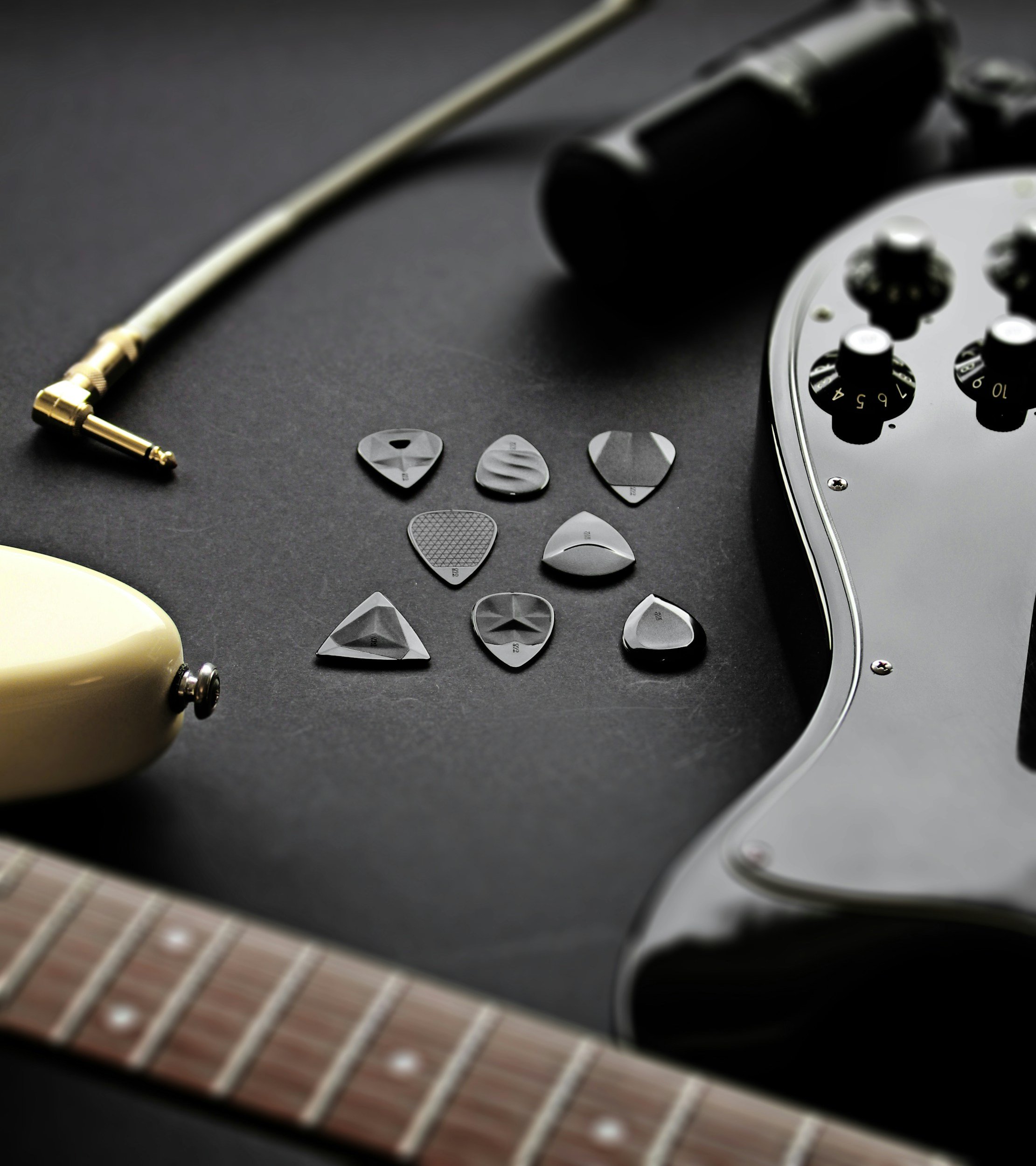 Electric guitar with guitar picks and a guitar capo on a black surface.