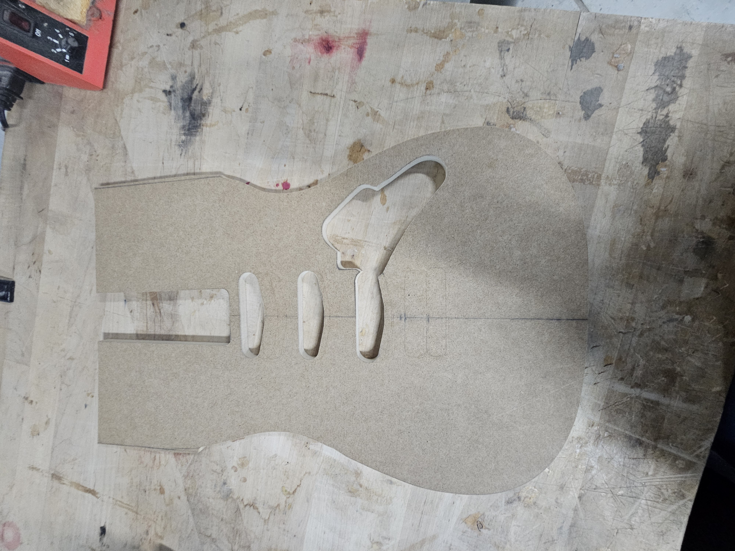 Wooden laser cut guitar body shape on a work table.
