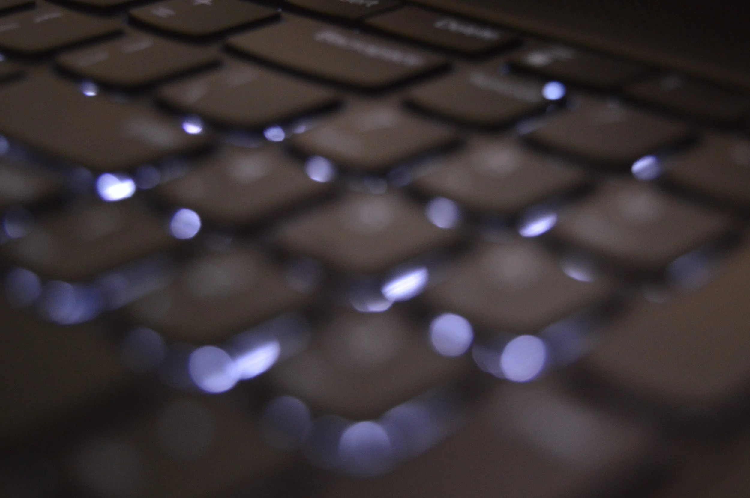 Close-up of a black computer keyboard with backlit keys and glowing lights.
