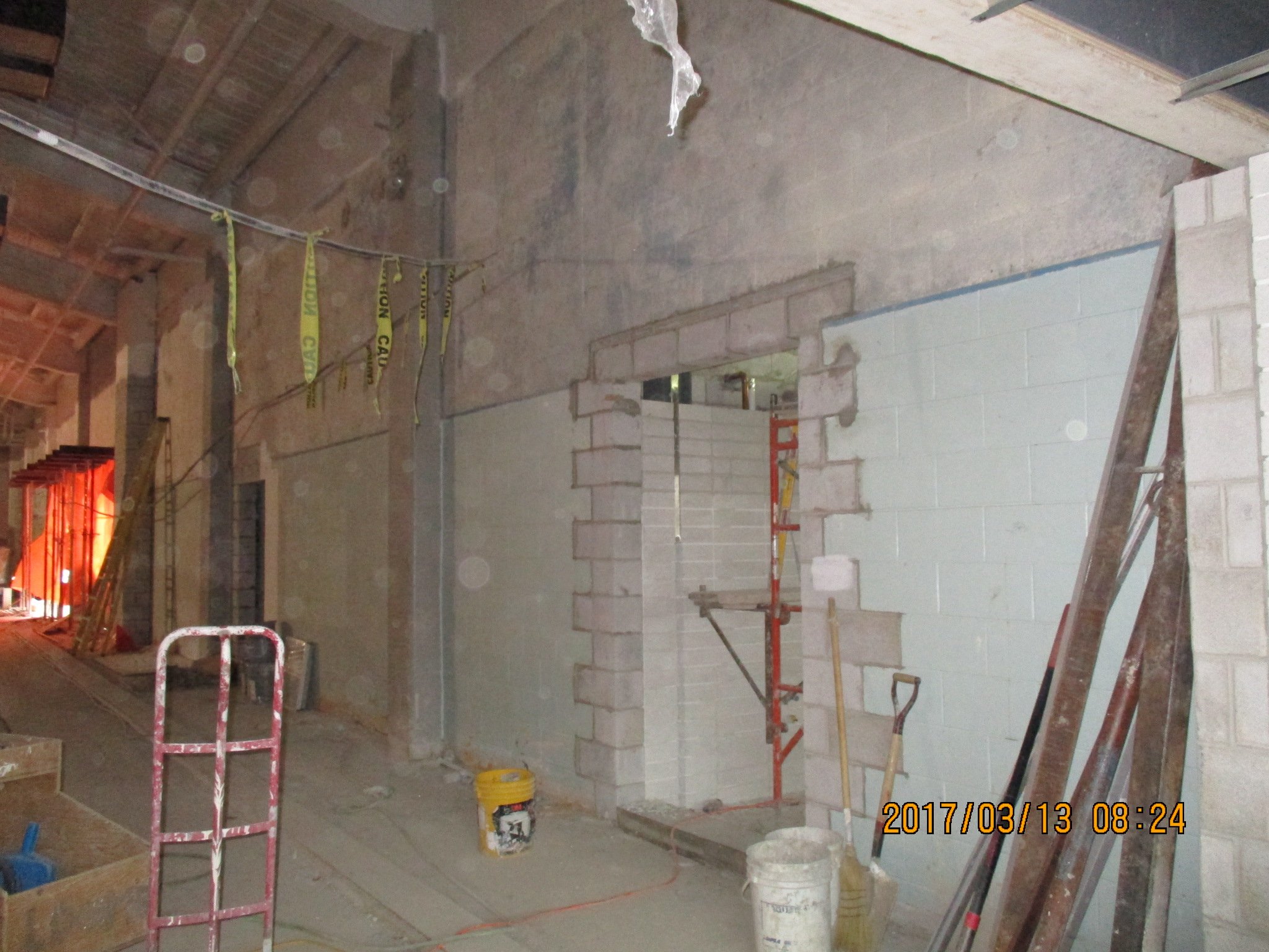 Construction site with building materials, tools, and scaffolding inside a partially built structure.
