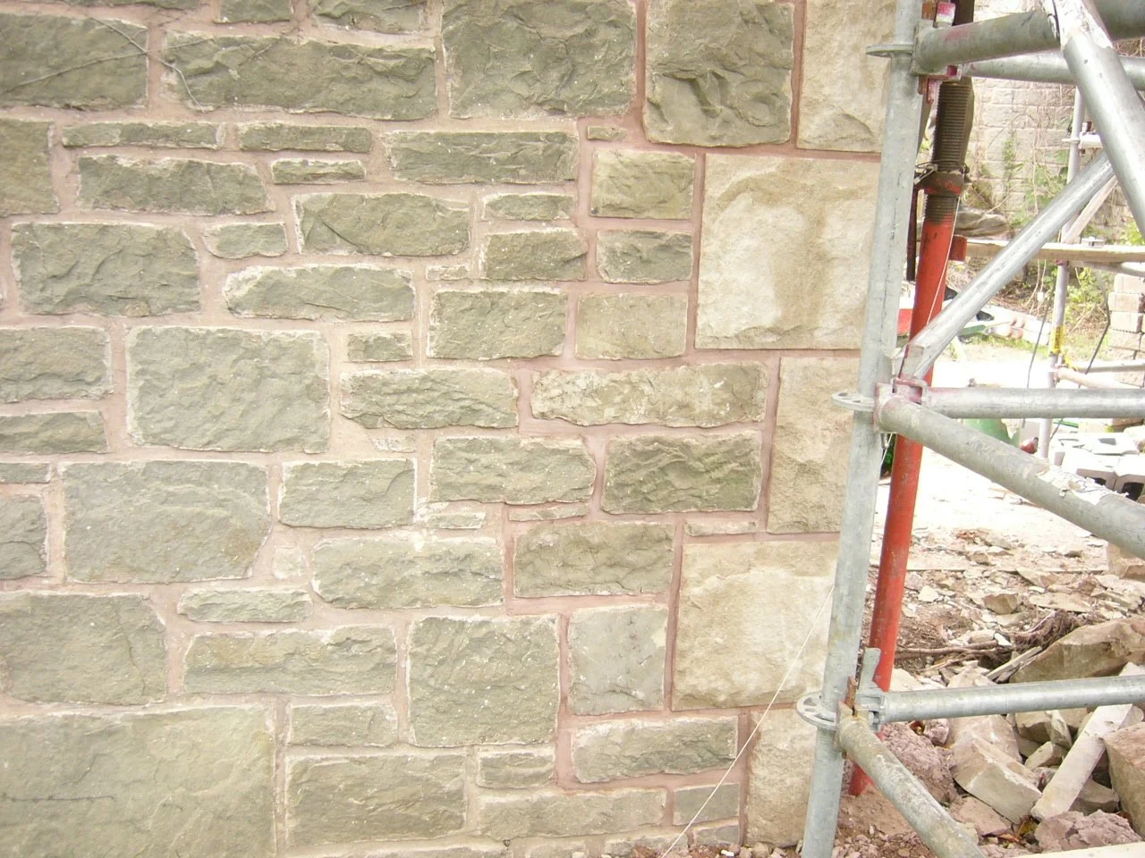 Close-up of a newly constructed stone wall with a plantation scaffold on the right side.
