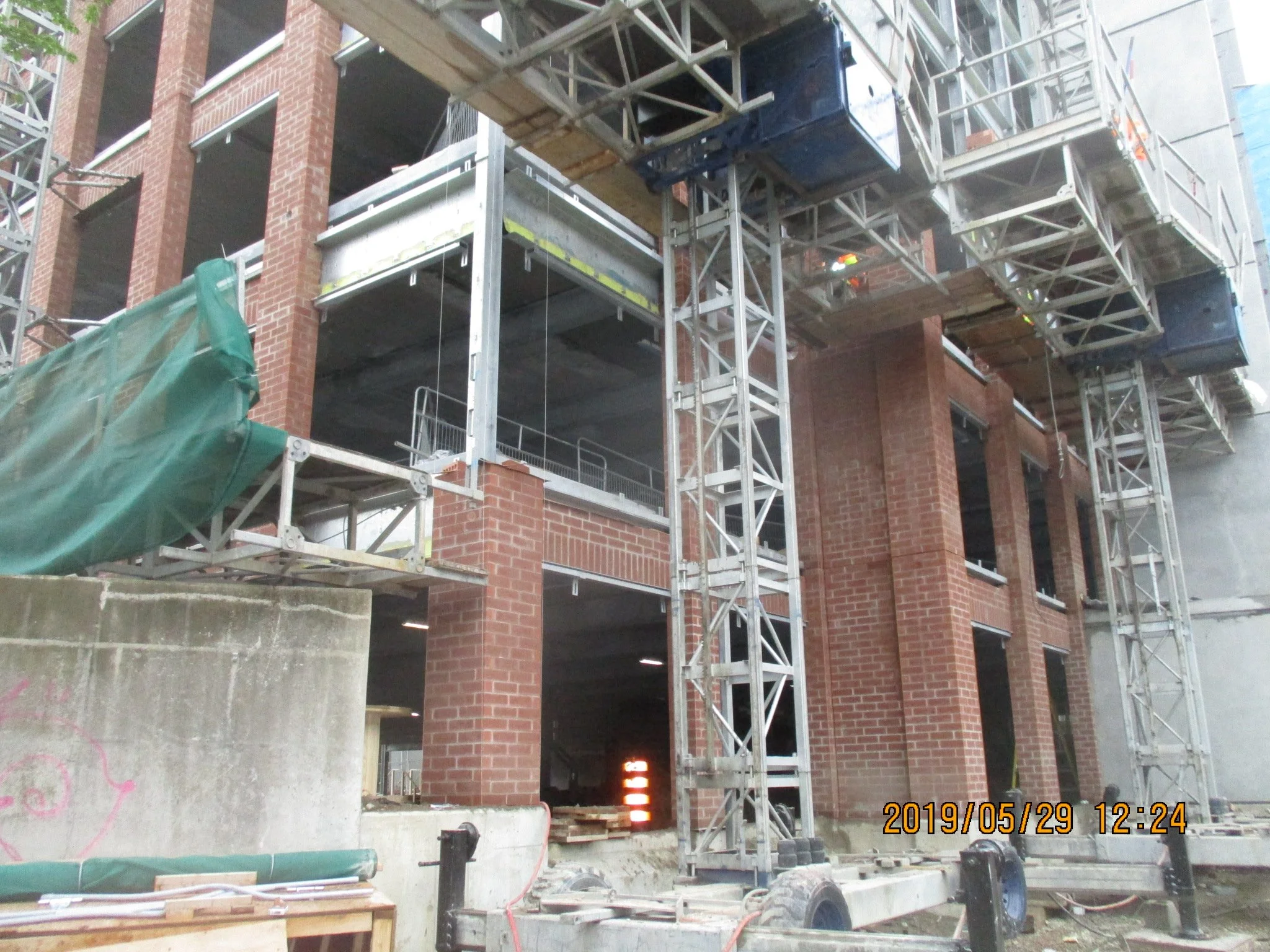 Construction site with a partially built brick building, metal scaffolding, and construction equipment.