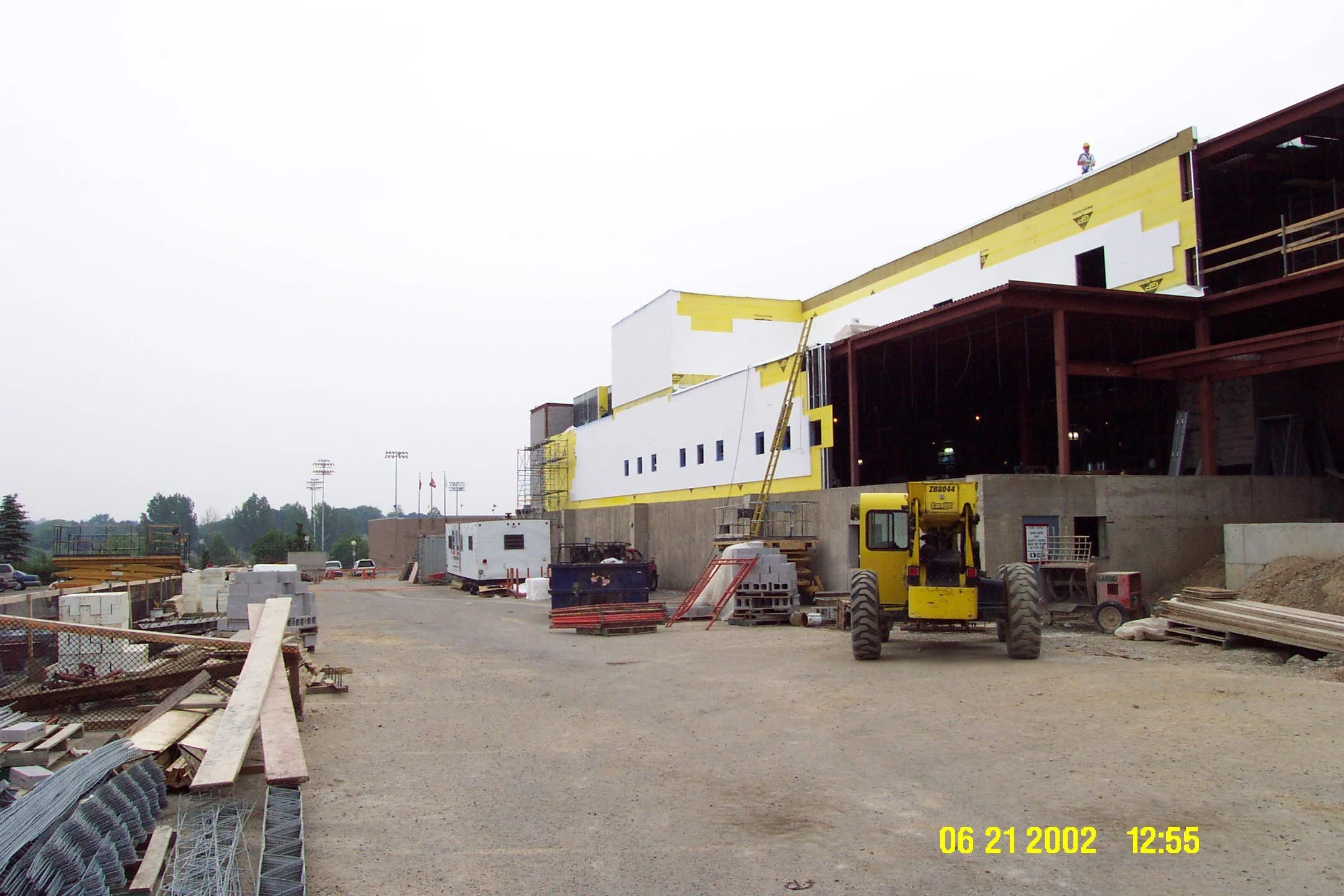 Construction site with building under construction, construction equipment, and materials, overcast sky.