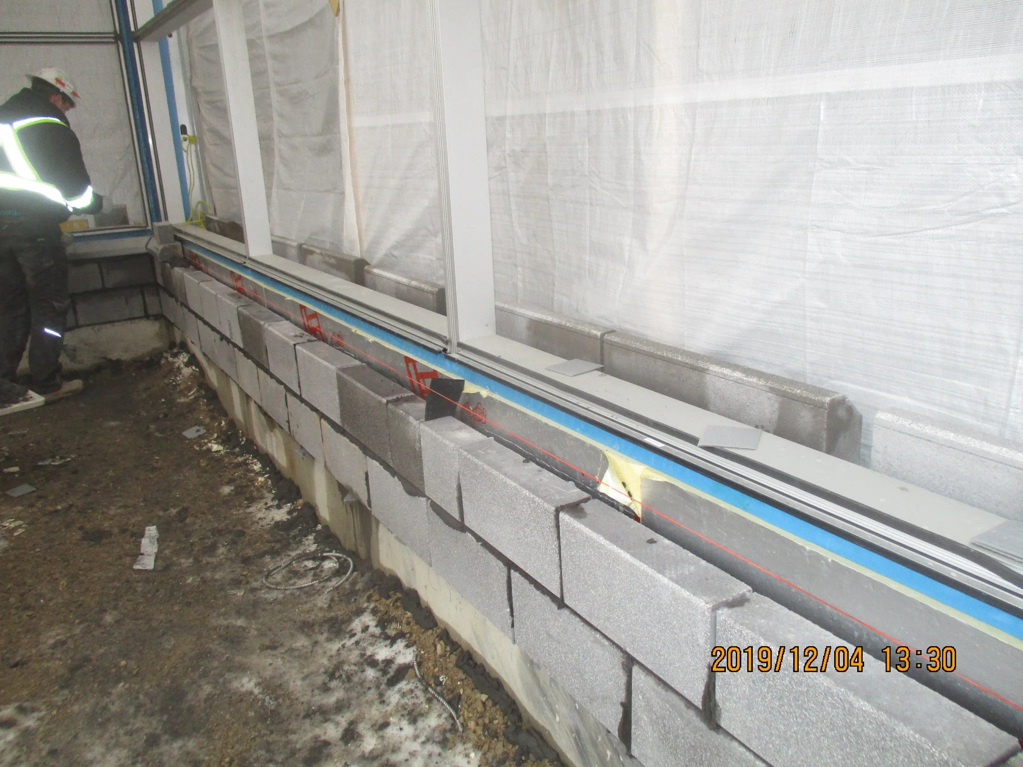 Construction worker working on a brick wall in an indoor building under construction.