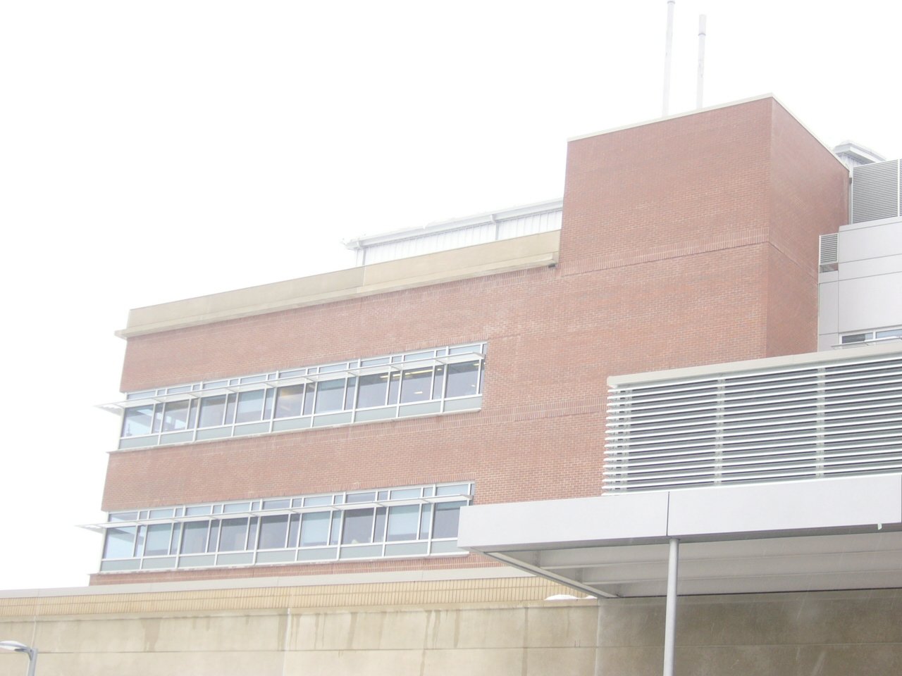 Close-up of a modern multi-floor office building with brick and metal siding and large windows.