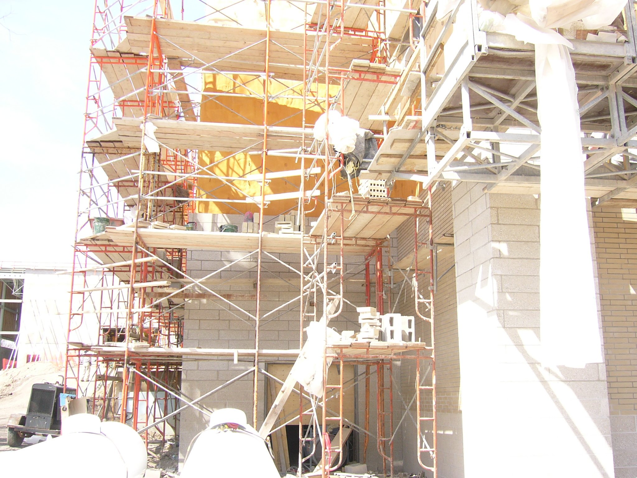Construction site with scaffolding and partially built brick walls.