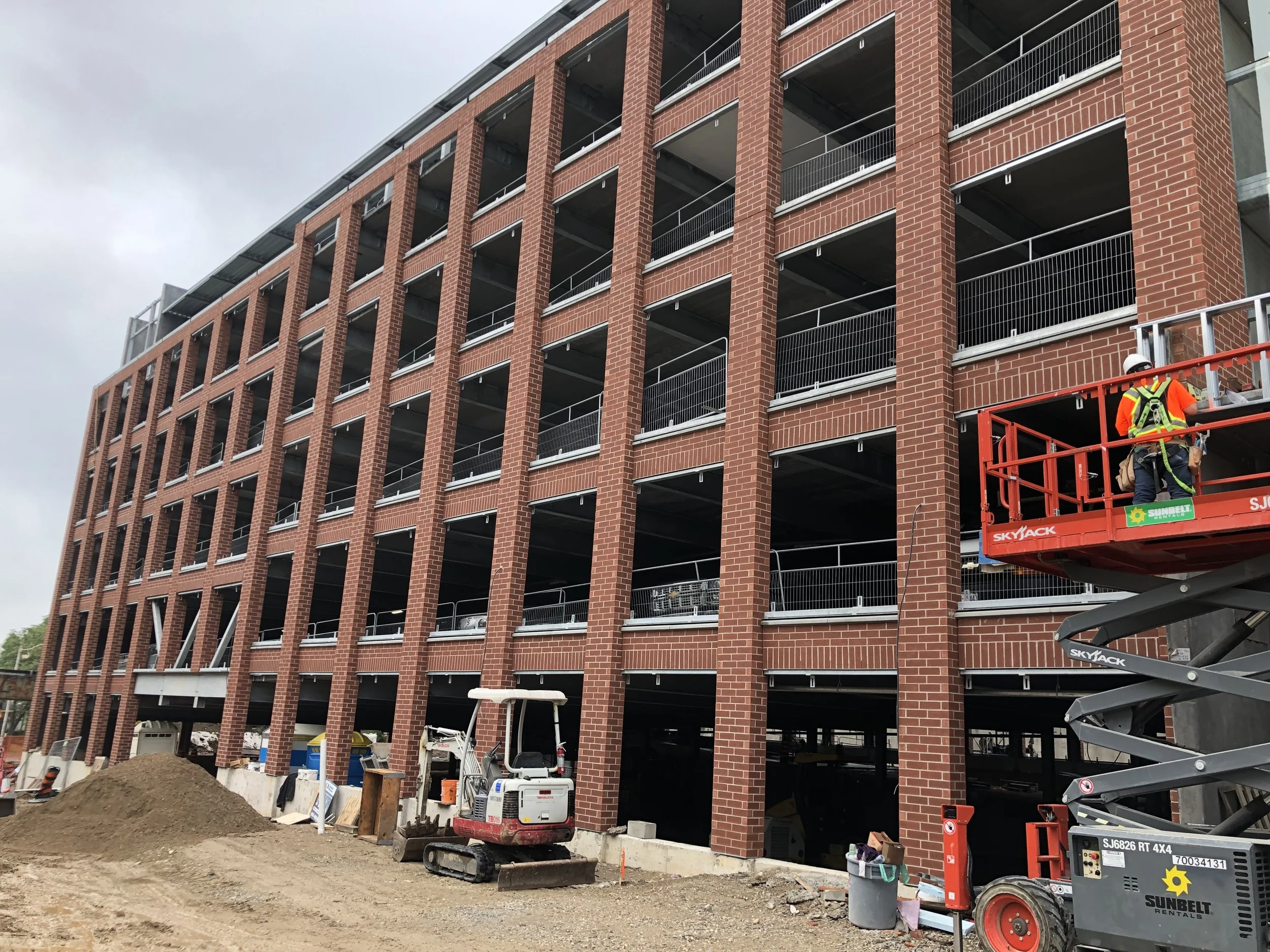 Construction workers on a red lift working on a multi-story brick building.