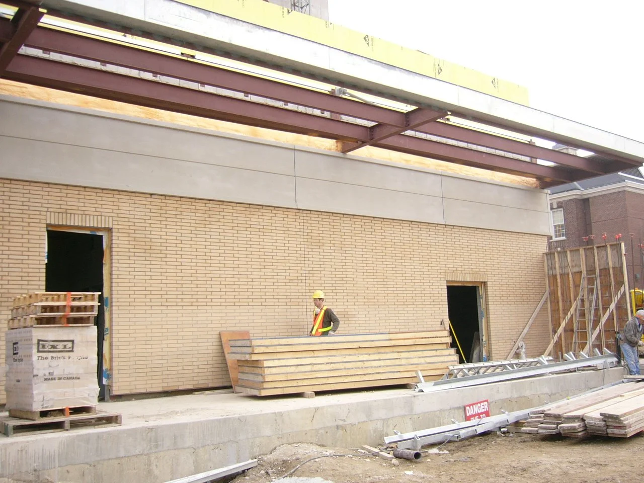 Construction site with workers, building materials, stair scaffolding, and a brick wall under construction.