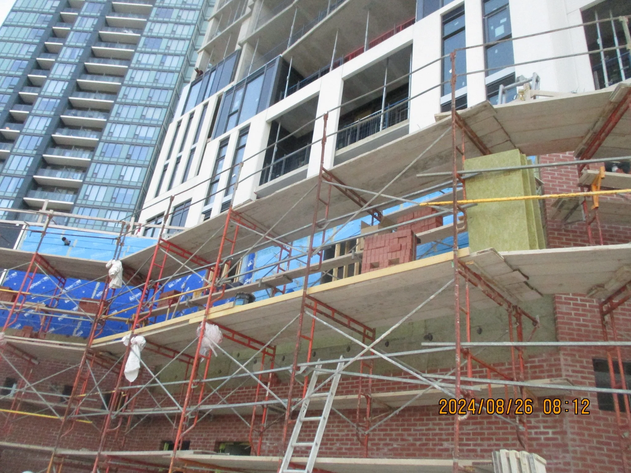 Construction site with scaffolding around a building with brick and glass exterior.