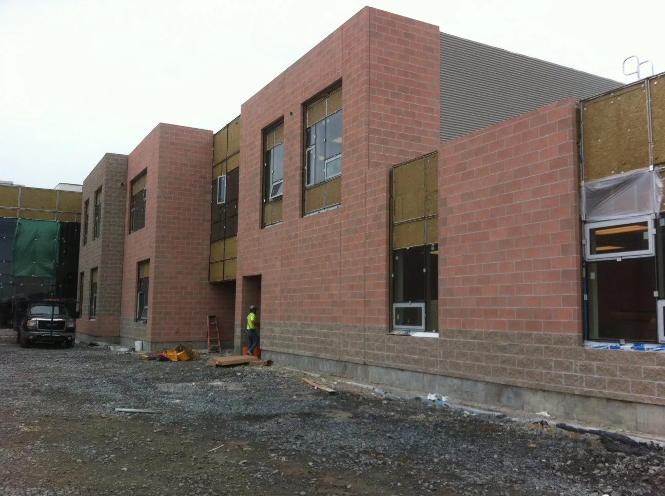 Construction site of a modern building with brick walls, windows, and construction workers on site.