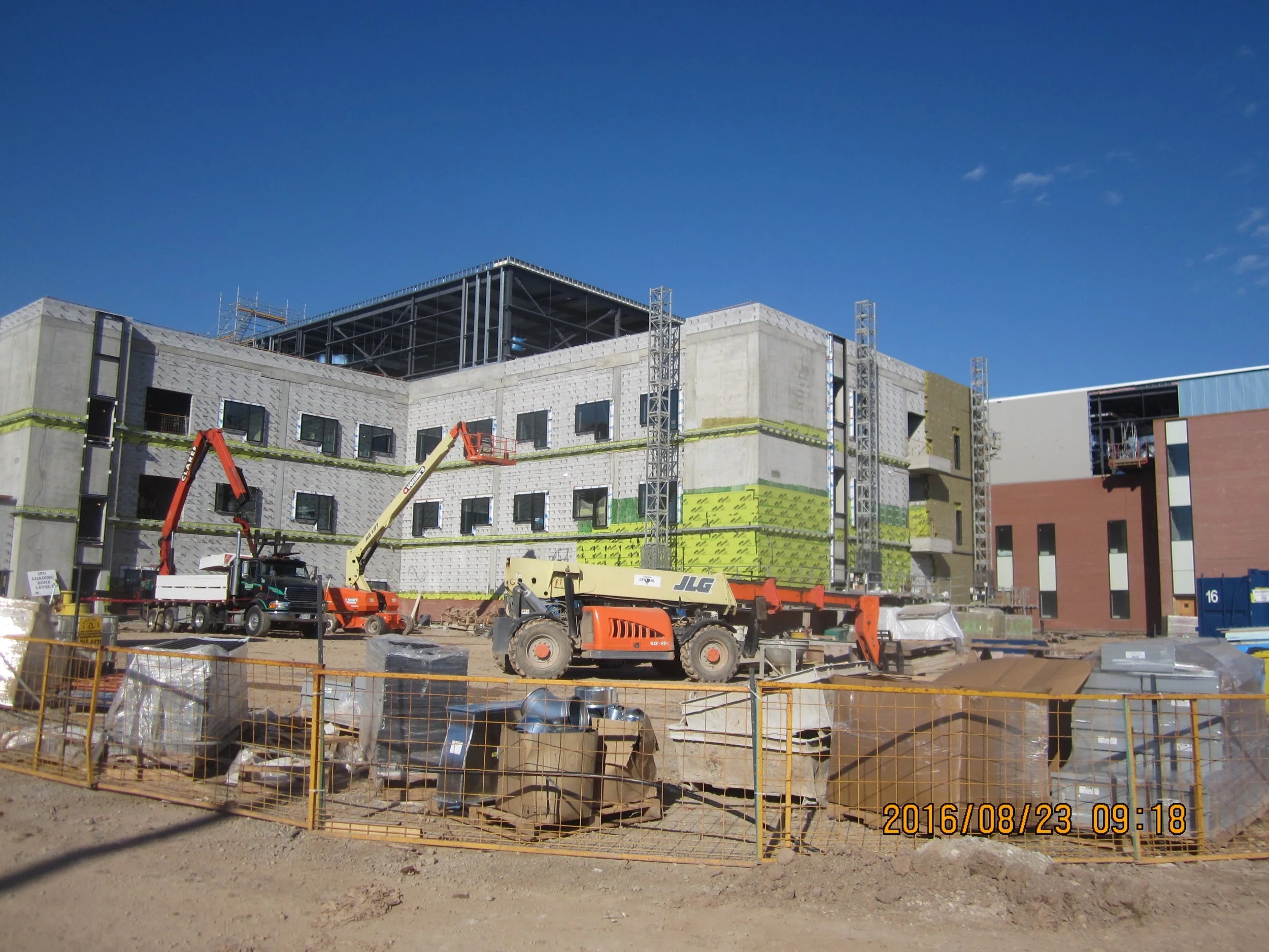 Construction site with partially built building, construction equipment, and safety barriers.
