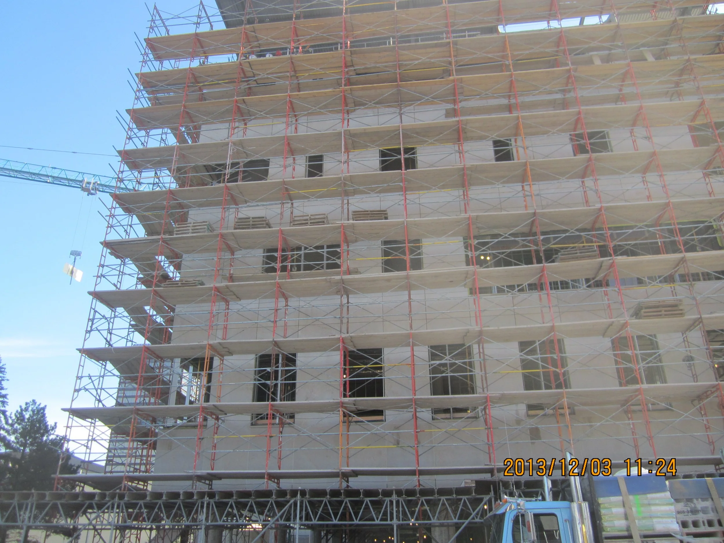 Building under construction with numerous scaffolding in front, multiple floors visible, a crane on the left side, and the date and time 2013/12/03 11:24 at the bottom right corner.