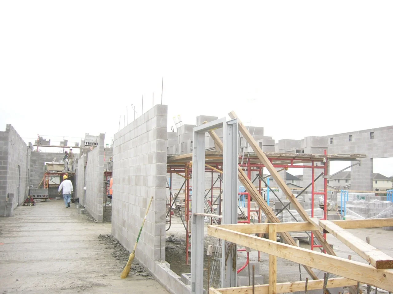 Construction site with workers building brick walls and scaffolding for a new building.