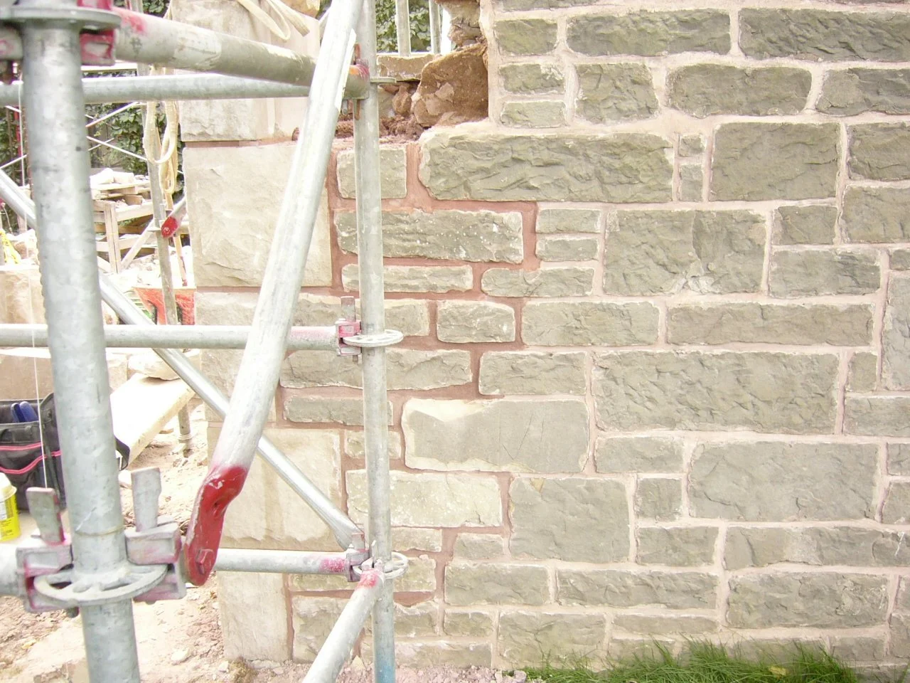 A brick wall under construction with a metal scaffold partially visible in front.