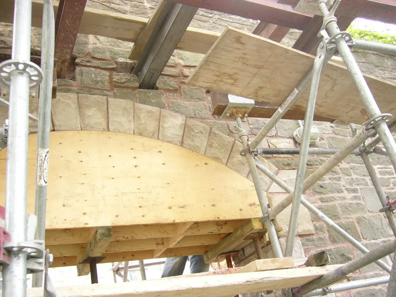Construction scaffolding and wooden boards working on brick building renovation.