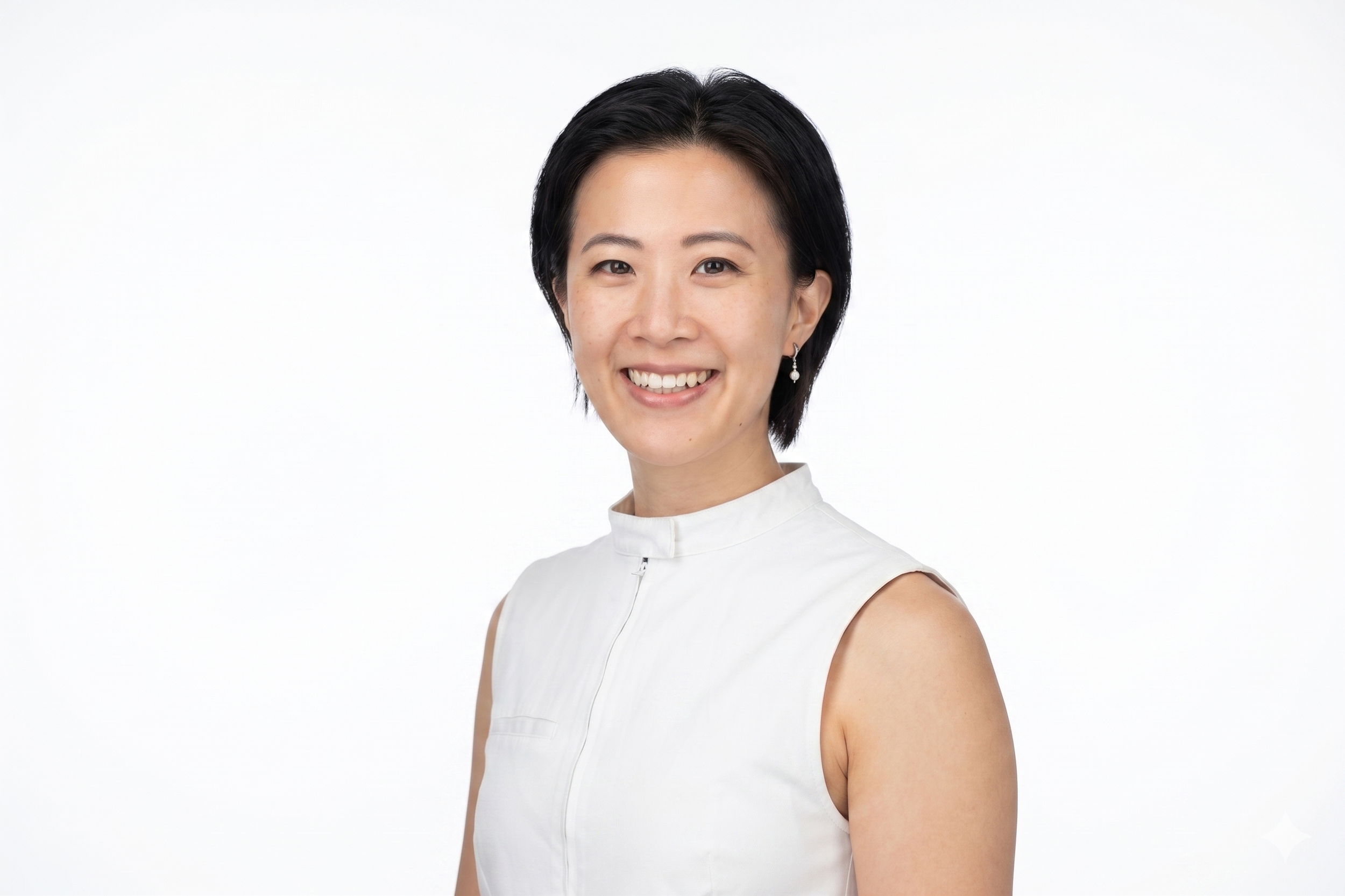 A woman with short black hair and earrings smiling against a white background.