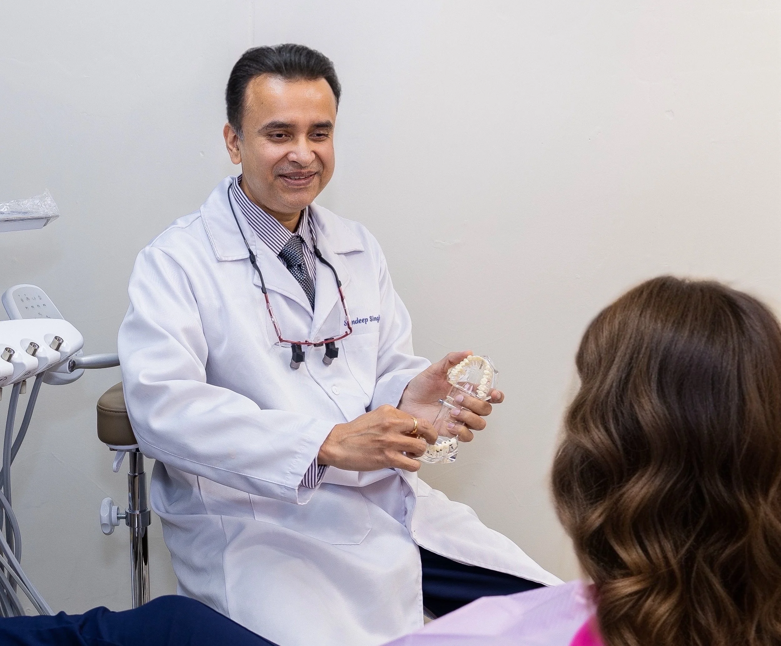 Dr. Singh explaining dental models to a patient in a dental clinic.