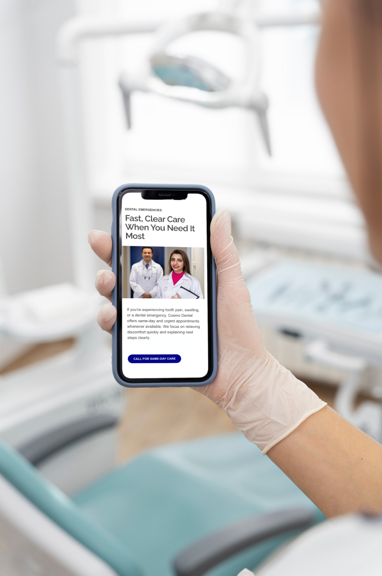 Person wearing a medical glove holding a smartphone with a Cosmo Dental dental emergency services webpage open, showing dentists and a call-to-action button, in a dental clinic.