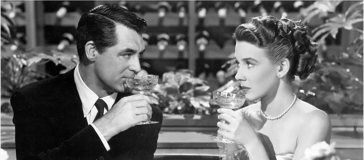 Romantic photo of a beautiful couple drinking champagne. Classic black and white Hollywood photo of Cary Grant and Betsy Drake with champagne glasses. From the 1948 film "Every Girl Should Be Married"