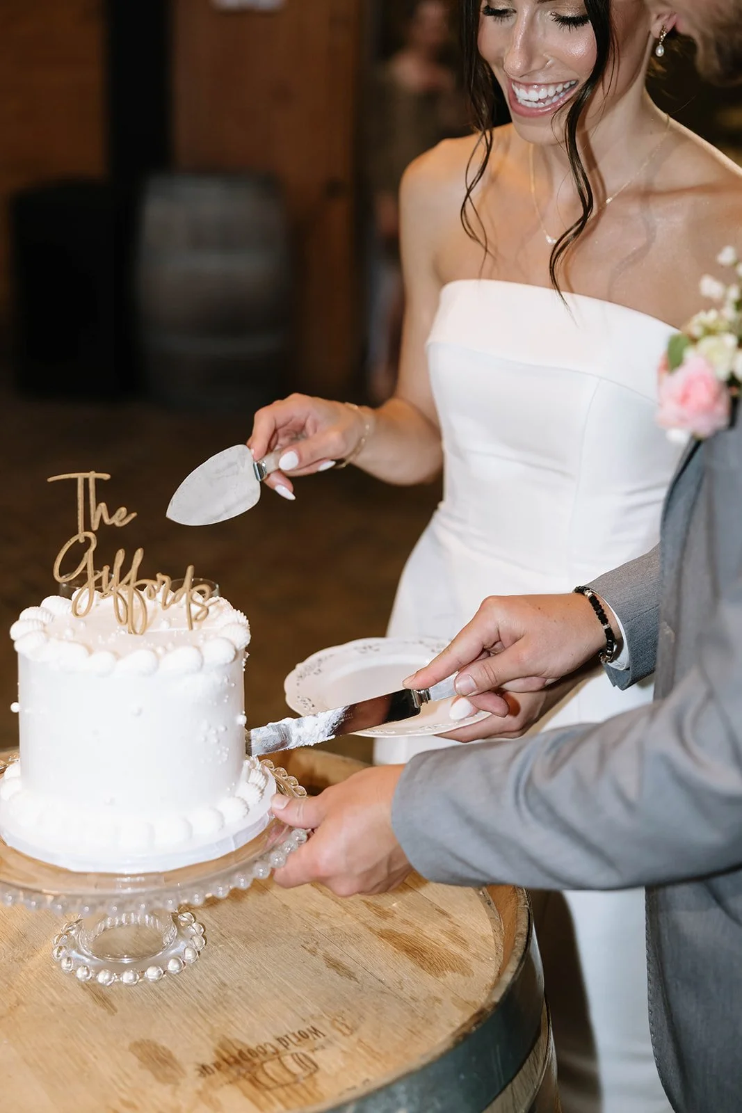Wedding bride in white dress cutting a wedding cake with a groom in suit.