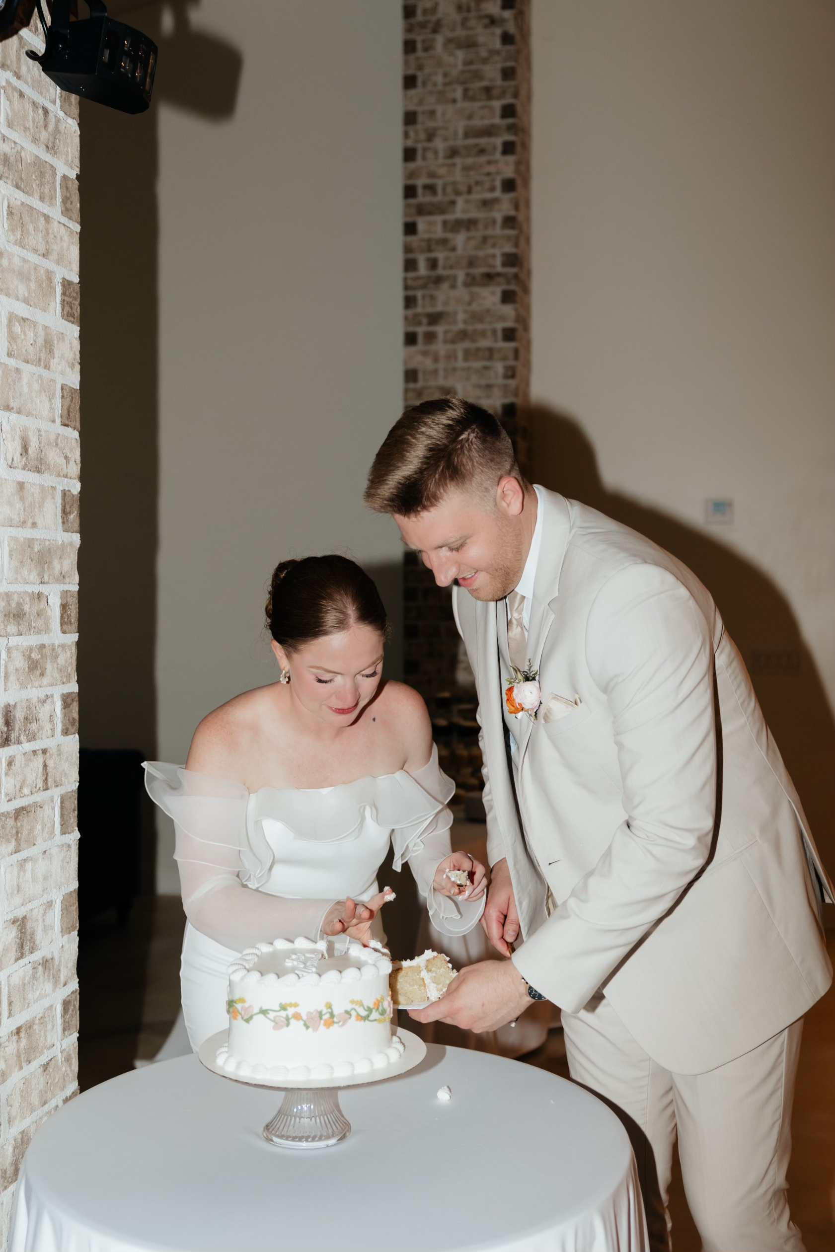 A bride and groom cutting a wedding cake together during their wedding reception.