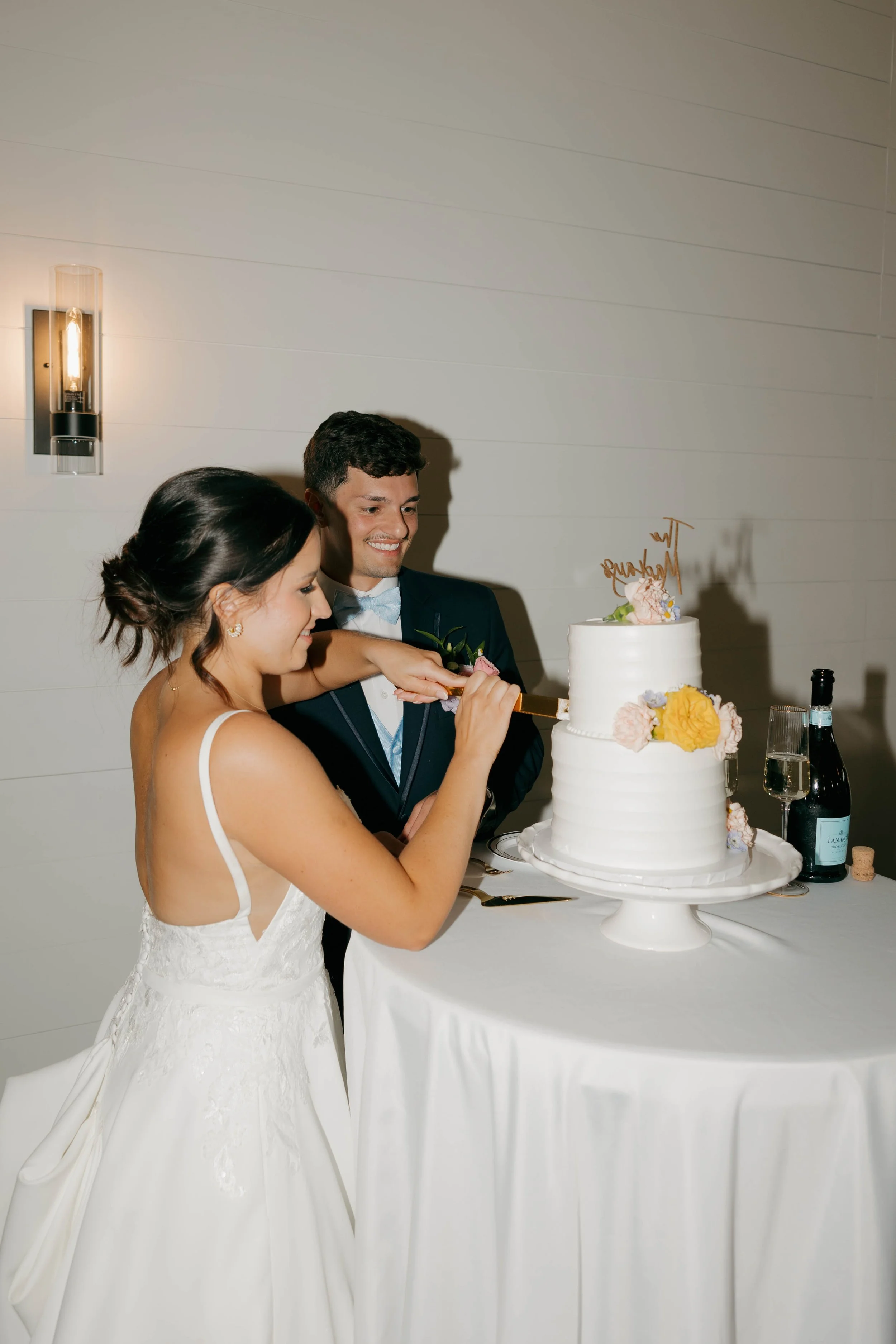 A bride and groom cutting a wedding cake together at their reception.