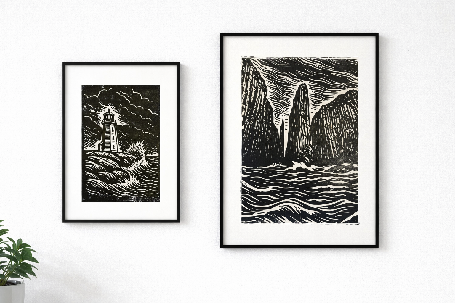 Two framed black and white landscape prints on a white wall. The left depicts a lighthouse on a rocky coast with waves crashing and a stormy sky. The right features rocky cliffs or sea stacks with rough water below and dramatic clouds above.