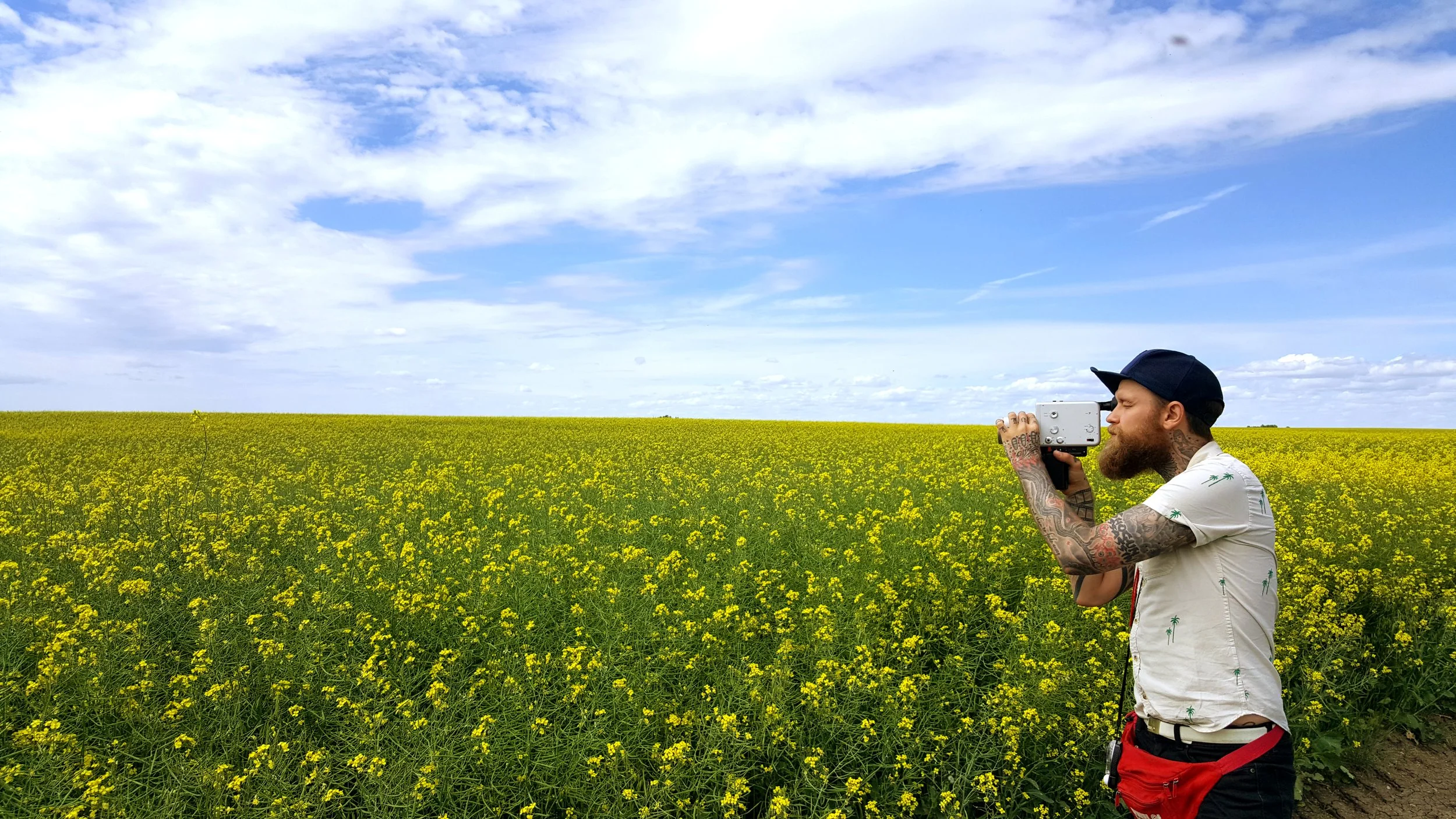 Reggie Grey filmming a canola field with an 8mm camera