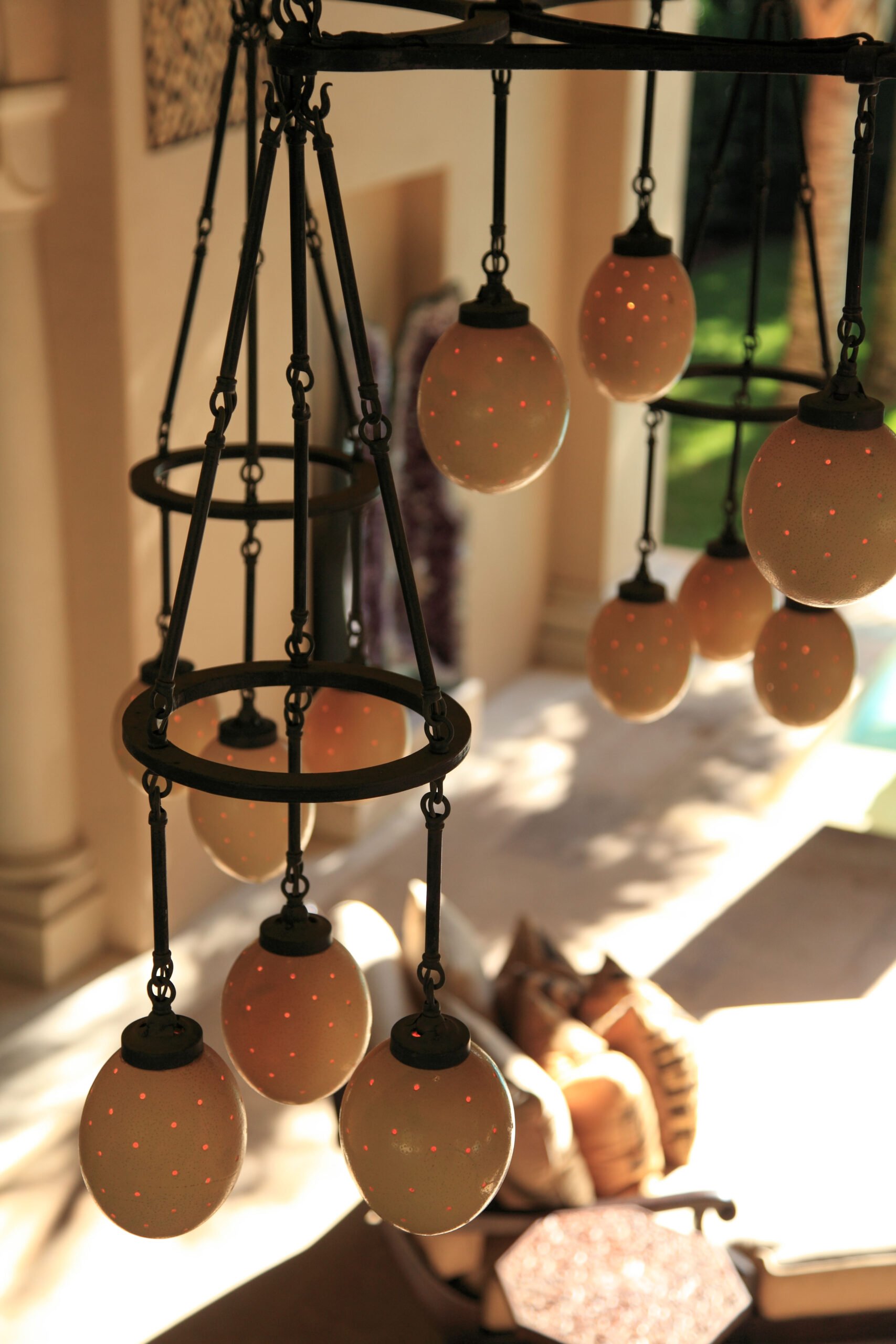 A chandelier with egg-shaped light fixtures hanging from a black metal frame, illuminated with small red dots.