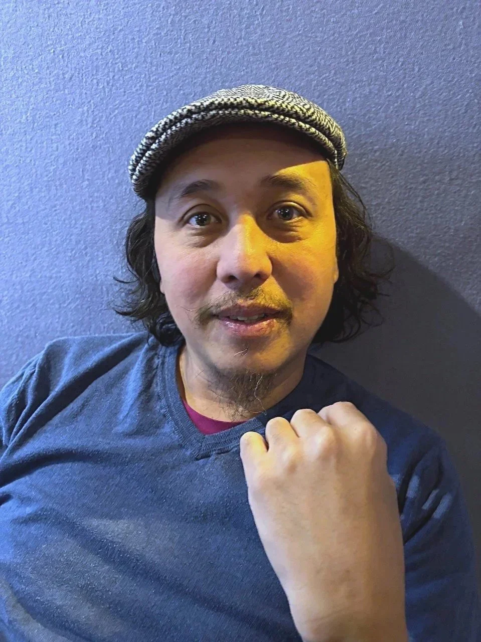 A man with curly black hair, wearing a black and white checkered cap. This is Chair Tamayo, sound designer and composer for Liberty Scrap by Christina Masciotti directed and designed by T. Ryder Smith premiering at Culture Lab LIC in March 2026.