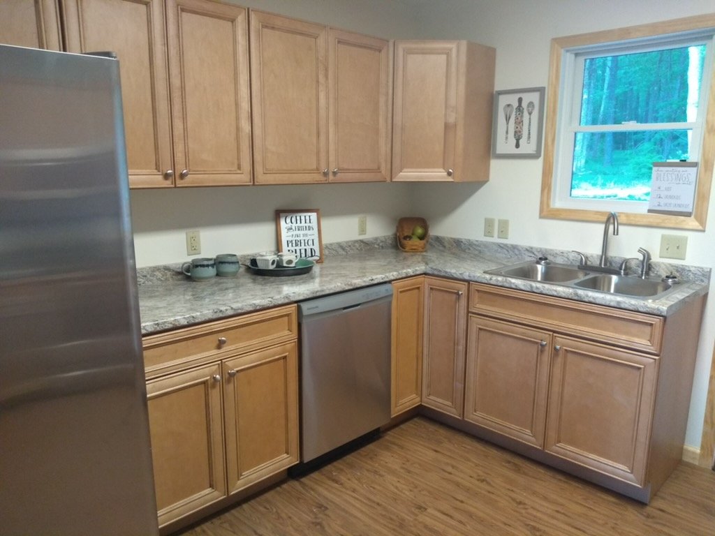 Modern kitchen with wood cabinets, a granite countertop, a window, and a stainless steel sink. All appliances are covered fully.