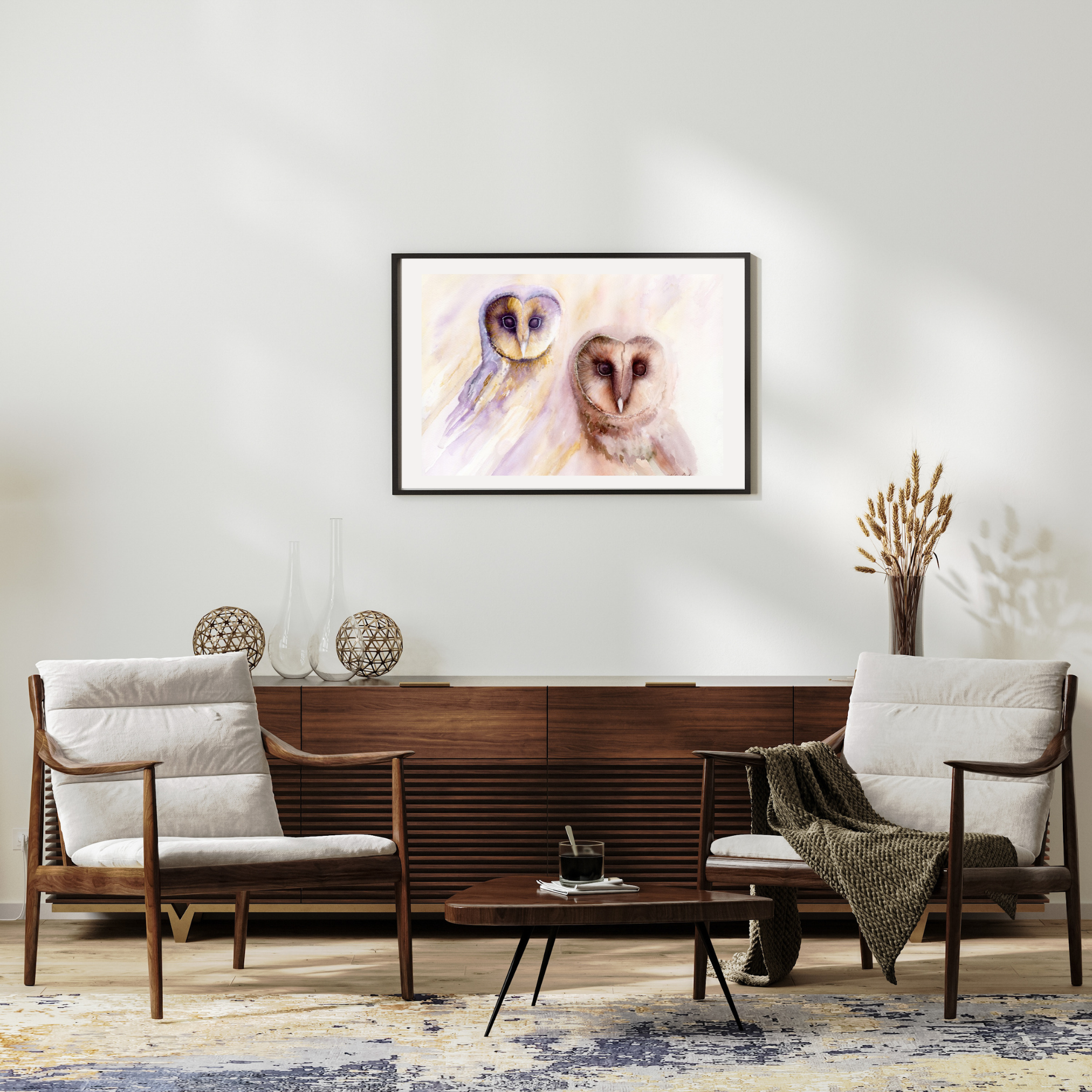 Owl's Wisdom framed barn owl art print hanging above a timber sideboard between two armchairs in a calm, neutral lounge room