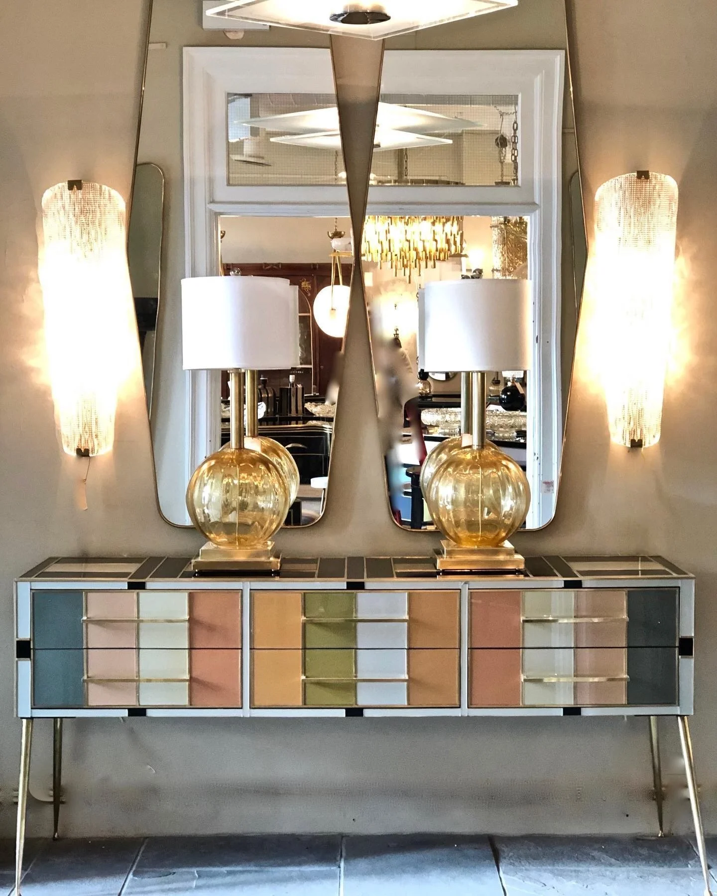 Shane Arron Design Put together this front hall deign with Italian Yellow Murano Glass Lamps with Long Unique Murano Glass wall sconces with Geo Ponti Style brass framed mirrors.  The star of the design is the multi Coloured Glass console from Italy.