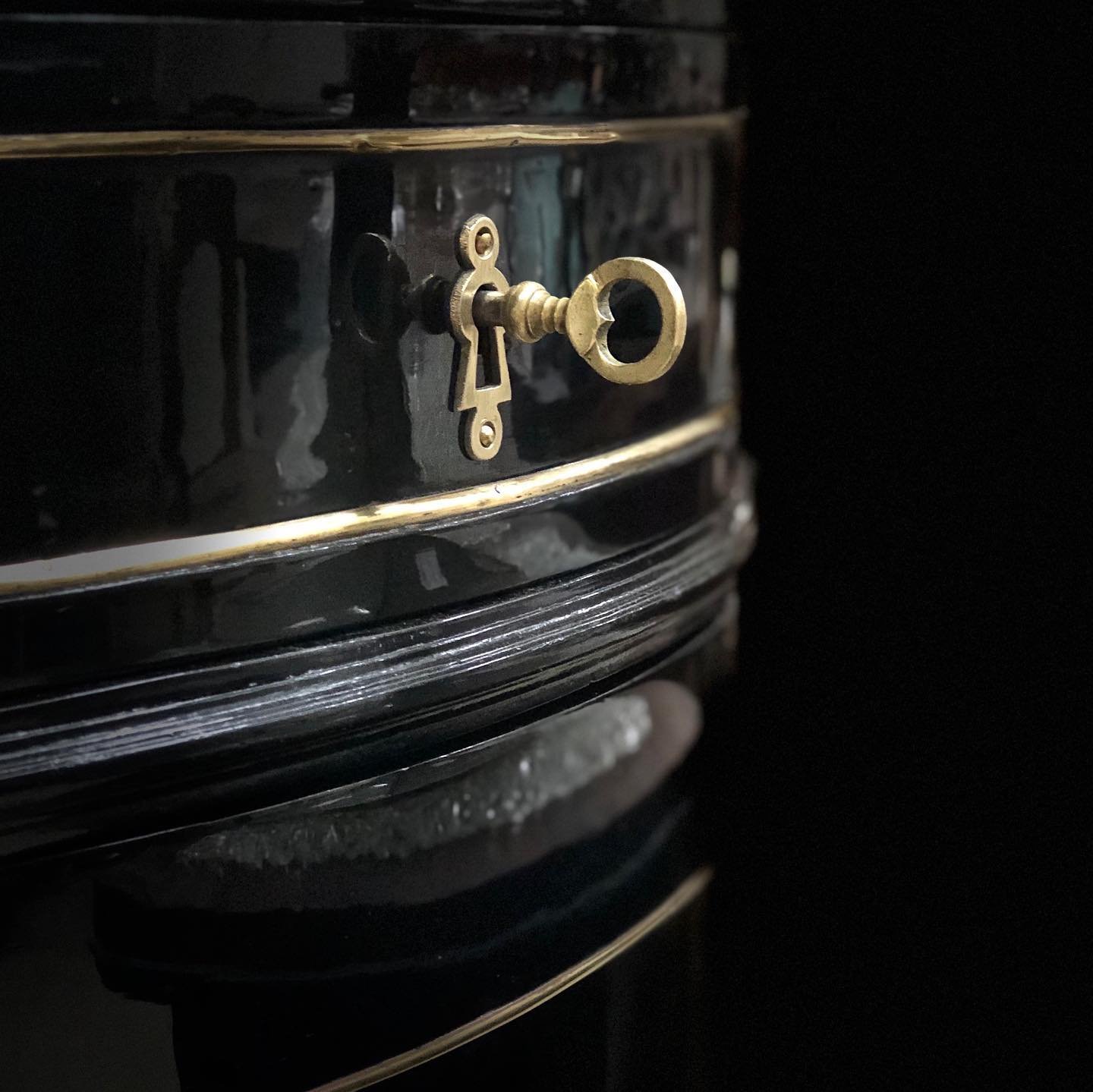 A close-up of a vintage black typewriter with a brass key in the foreground.