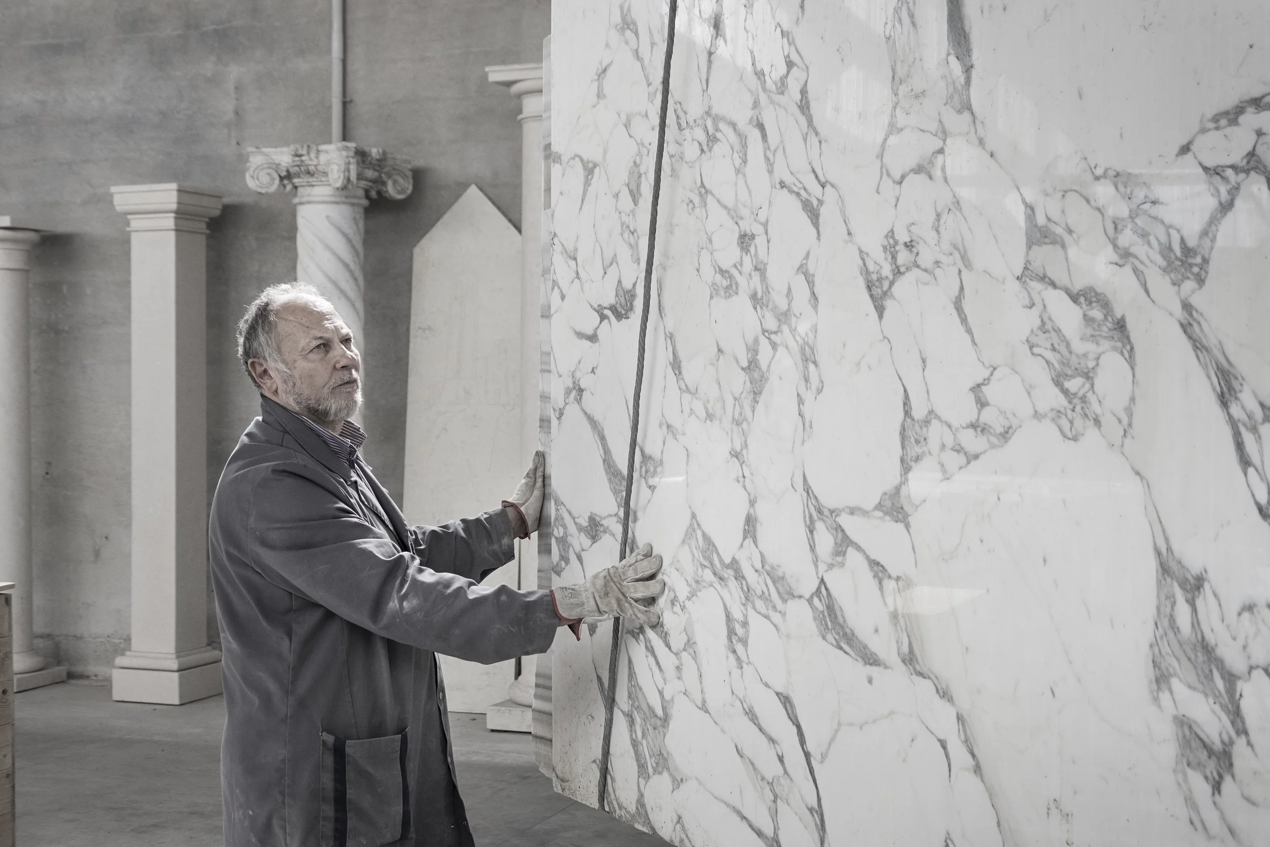 Italian marble craftsman inspecting a custom Calacatta marble slab for a bespoke luxury project in the USA