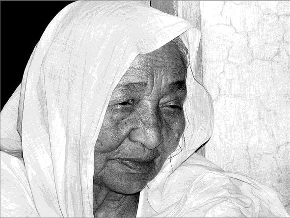 Close-up of elderly woman wearing a headscarf, with a solemn expression.