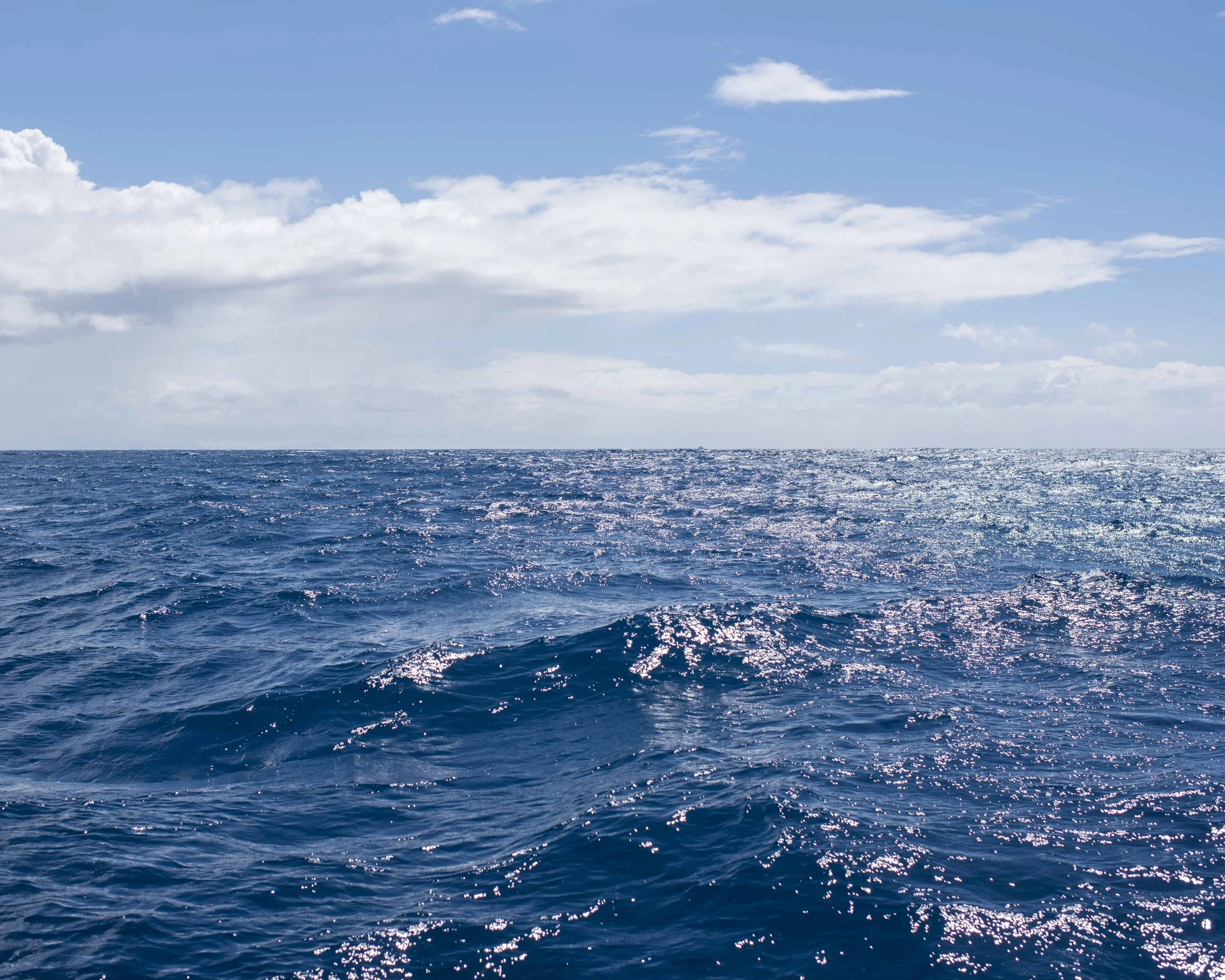 Open Hawaii ocean with blue water and a partly cloudy sky