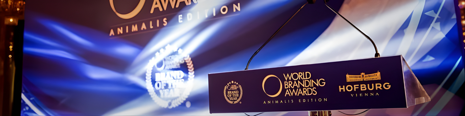 Close-up of a podium at the World Branding Awards Animalis Edition, with a dark blue background, and the logos of the awards and Hofburg Vienna hotel in gold.