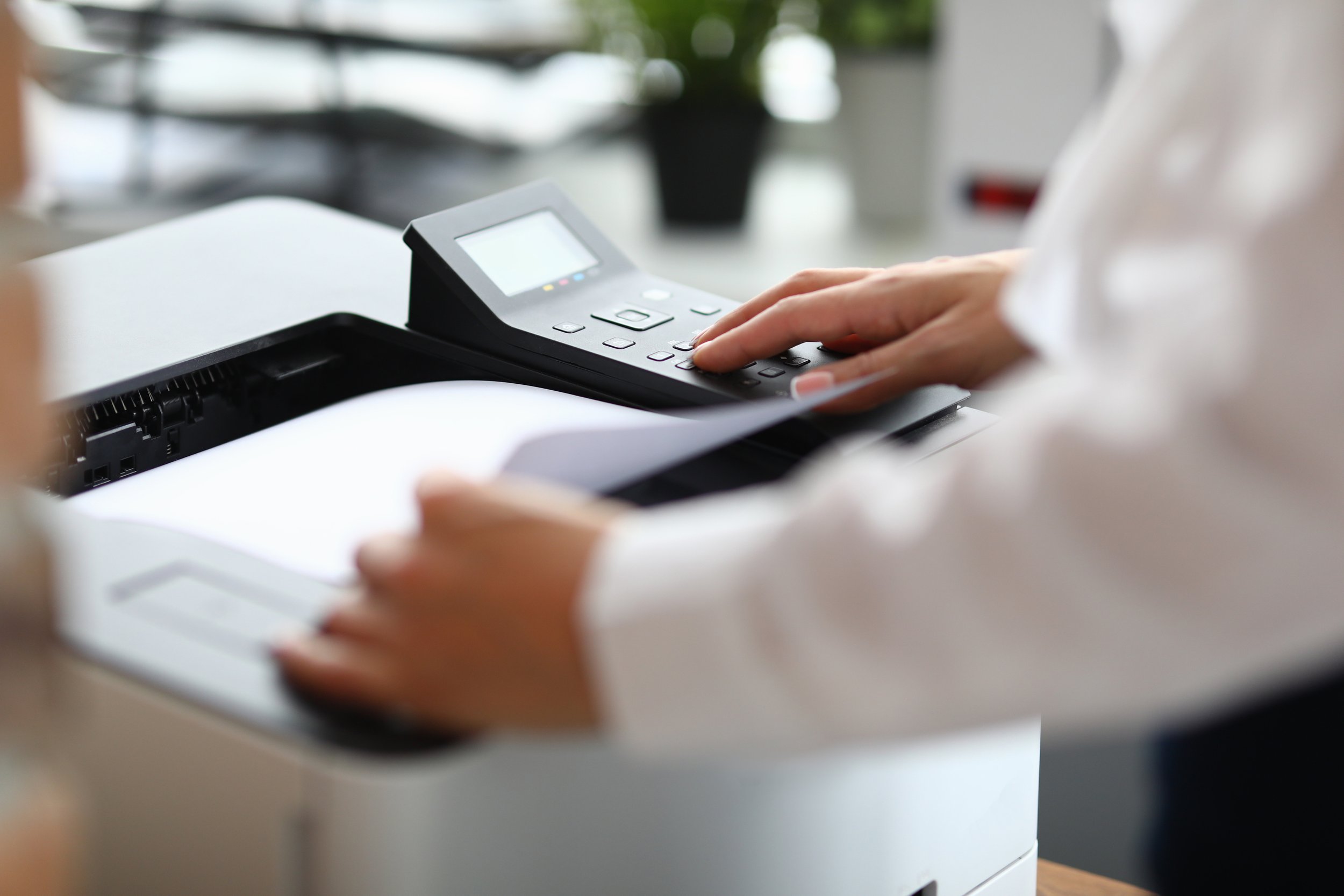 A person using a scanner to scan documents at a desk in an office.