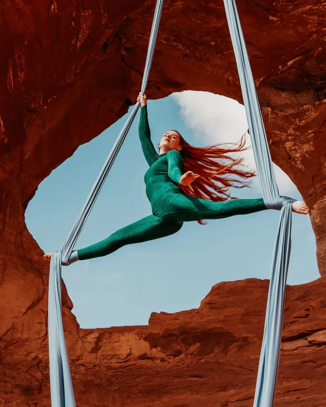 An aerial performer in front of a stone arch