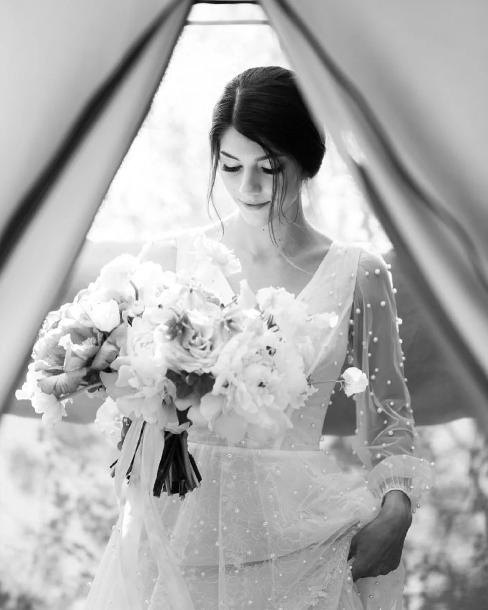 A bride wearing an elegant gown holding a bouquet of flowers