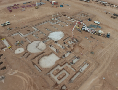 Aerial view of an archaeological excavation site with partially uncovered structures and three large round mounds of dirt.