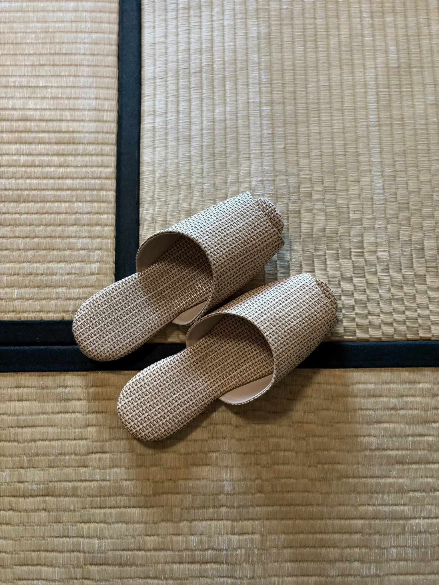Pair of woven slippers on a traditional Japanese tatami mat floor.